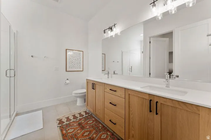 Full bathroom with double vanity, a stall shower, and light tile patterned flooring