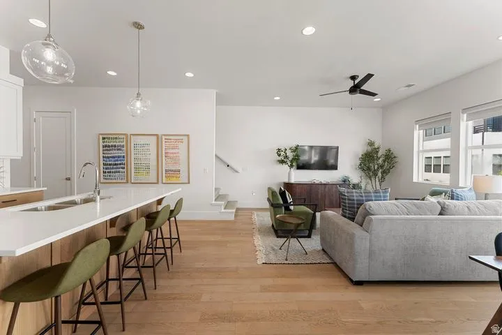Living room with light wood-style floors, recessed lighting, stairs, and ceiling fan
