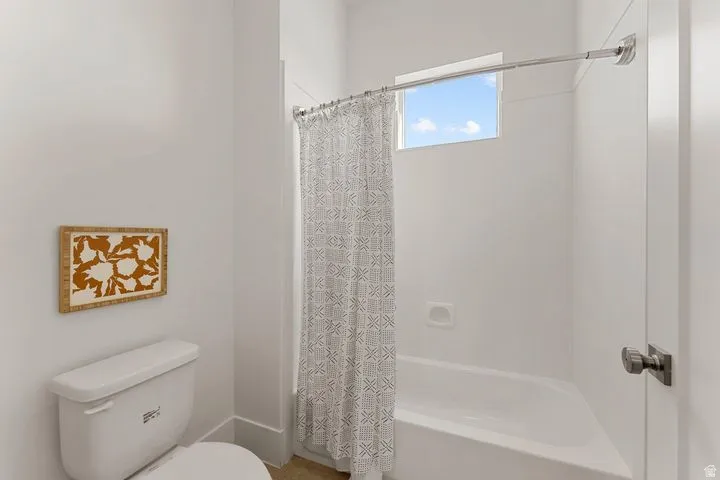 Bathroom with shower / bath combination with curtain and toilet