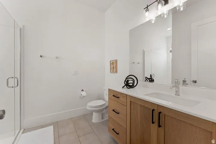 Full bathroom featuring a stall shower, vanity, and light tile patterned flooring