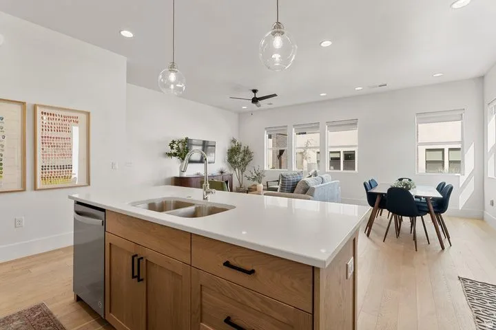 Kitchen featuring hanging light fixtures, light wood-style flooring, a center island with sink, stainless steel dishwasher, and recessed lighting