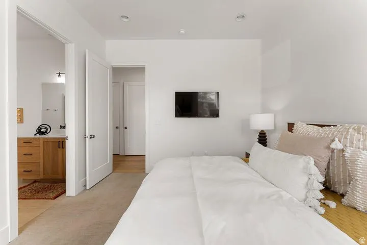 Bedroom featuring light carpet and connected bathroom