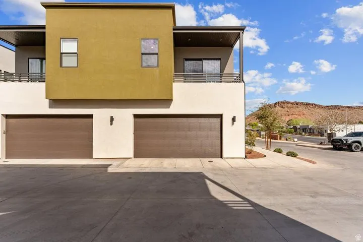 Back of house featuring stucco siding, a balcony, a mountain view, and a garage