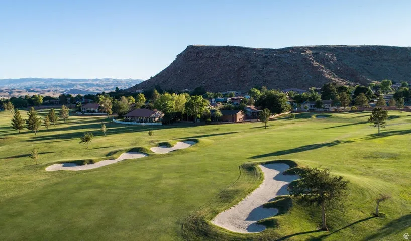 View of home's community featuring view of golf course, a mountain view, and a yard