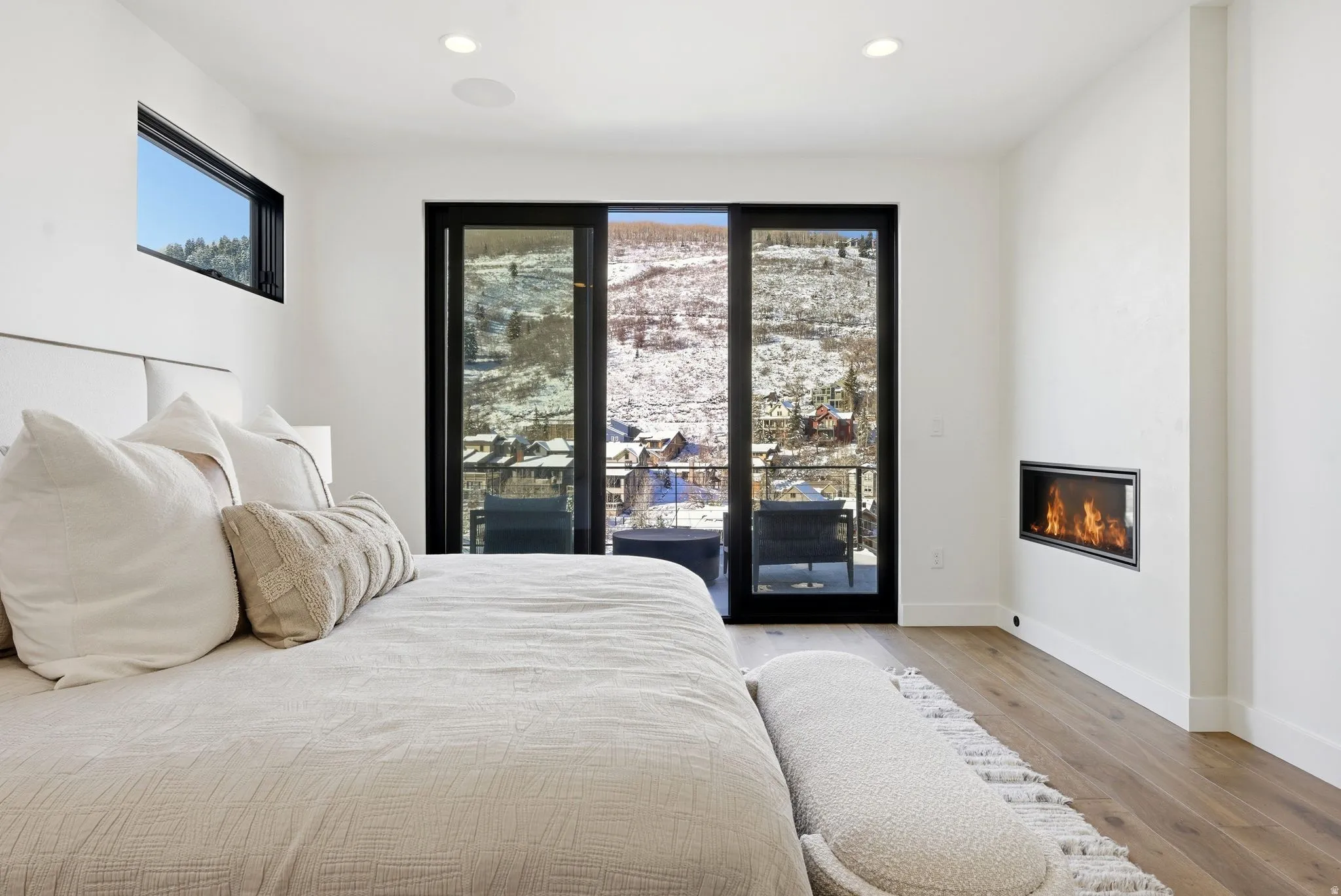 Bedroom with recessed lighting, access to exterior, a glass covered fireplace, and light wood-style floors