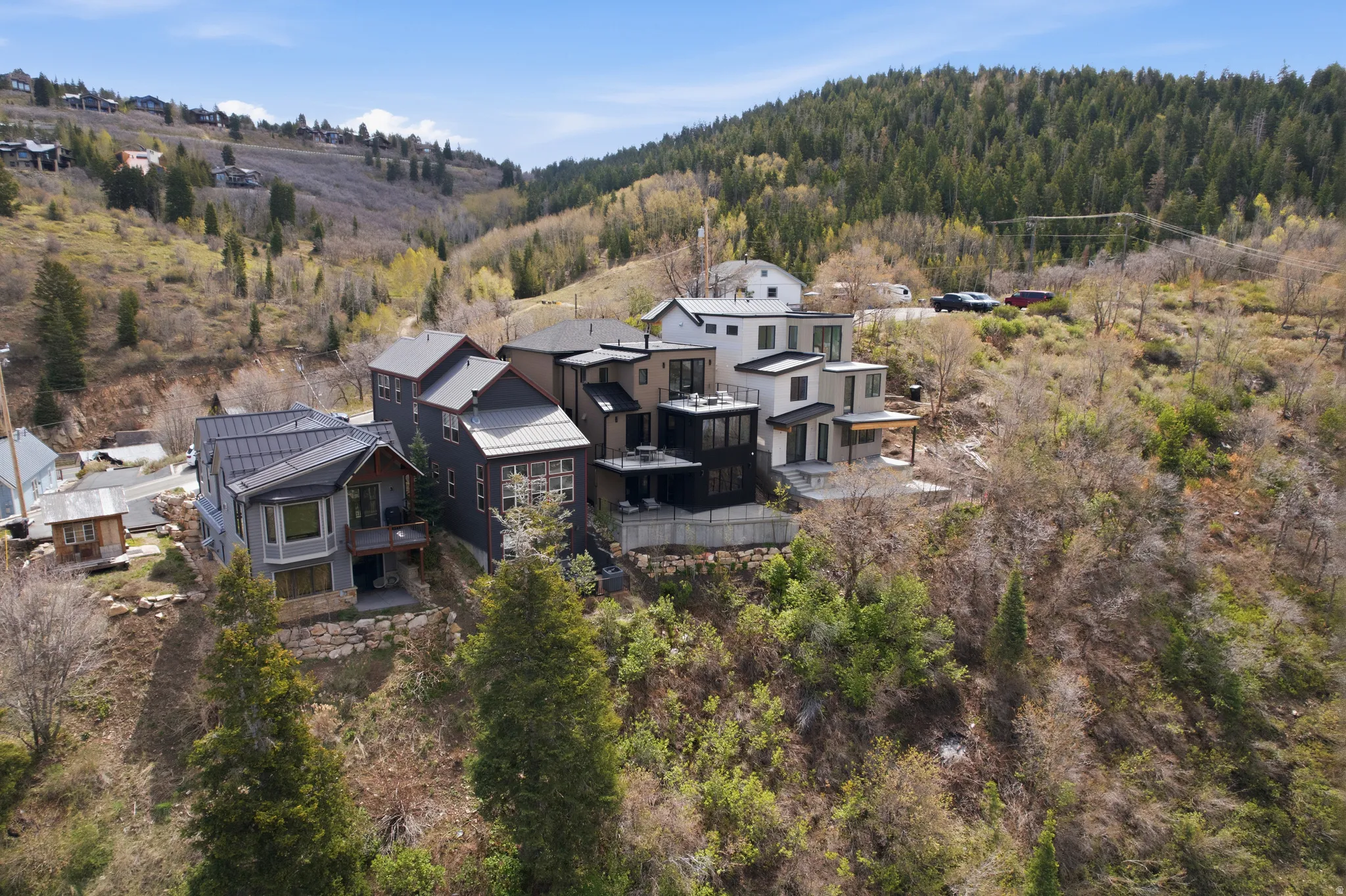 Hillside property featuring multi-level architecture, a dark metal roof, bay window, and a private balcony