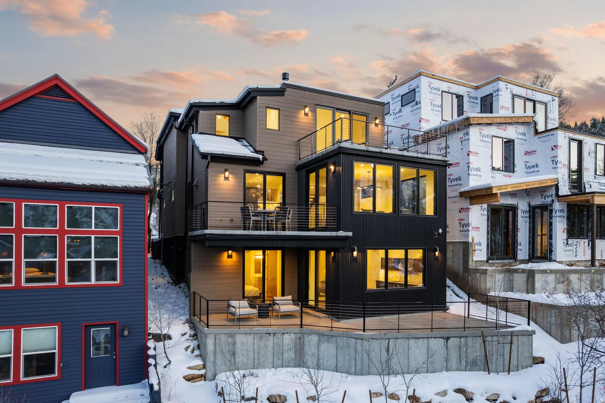 Snow covered rear of property with a balcony and board and batten siding
