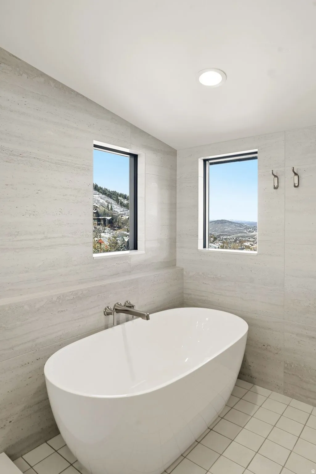 Bathroom featuring a freestanding bath, tile patterned flooring, tile walls, and vaulted ceiling