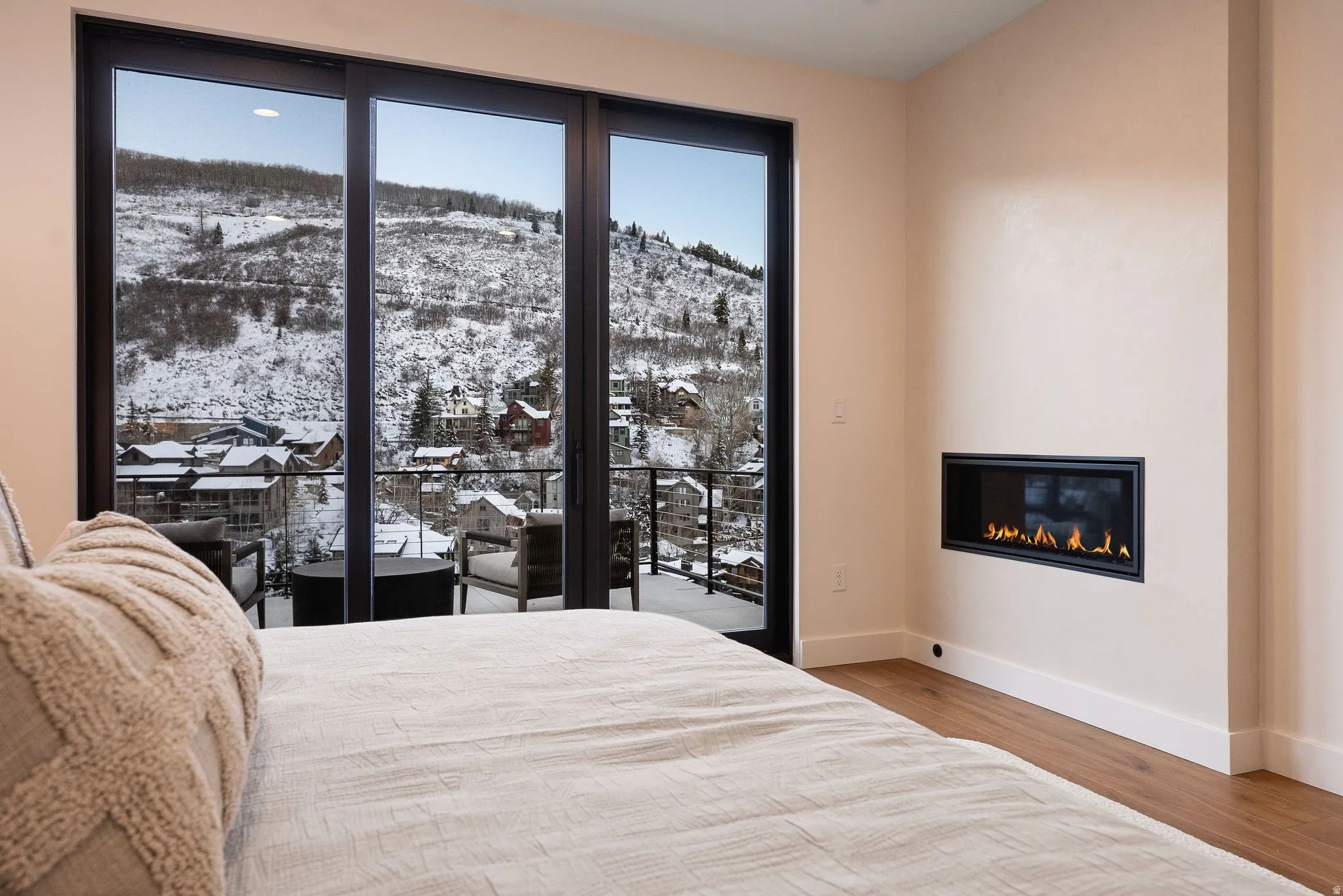 Bedroom featuring a mountain view, a glass covered fireplace, access to outside, and light wood-style floors