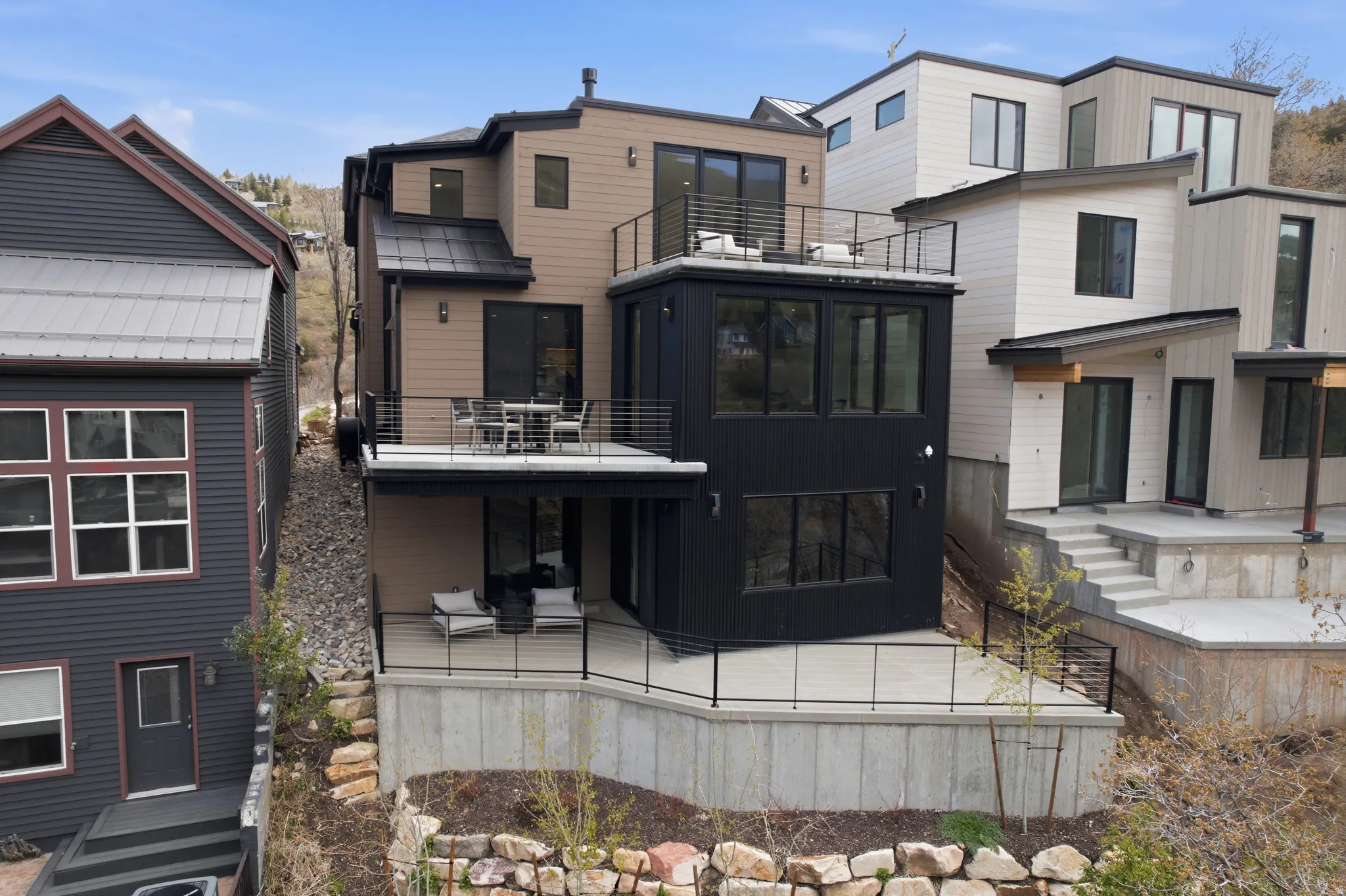 Multi-level modern residence featuring a tan and black exterior with abundant windows