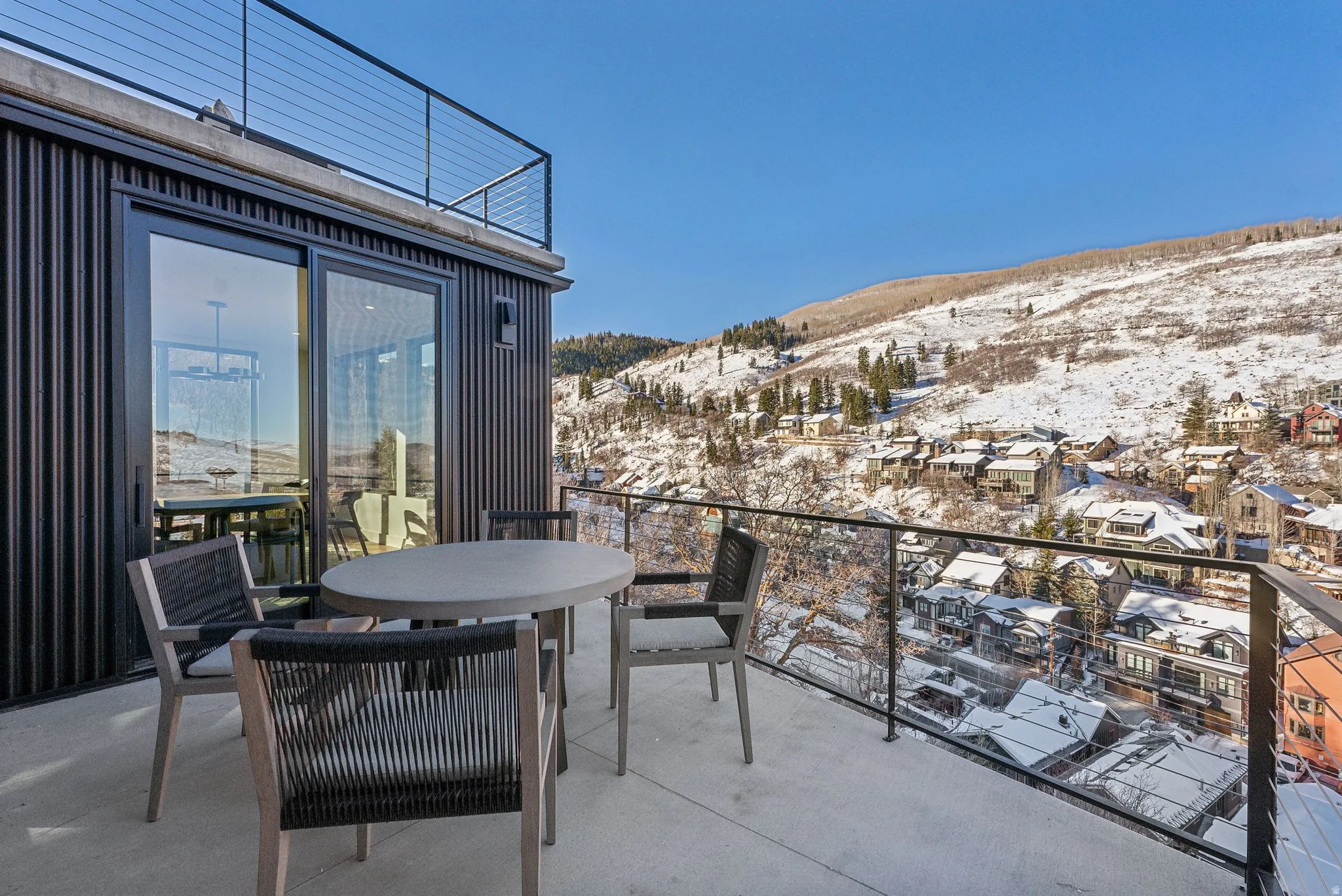 Snow covered back of property featuring a mountain view, outdoor dining space, and a patio