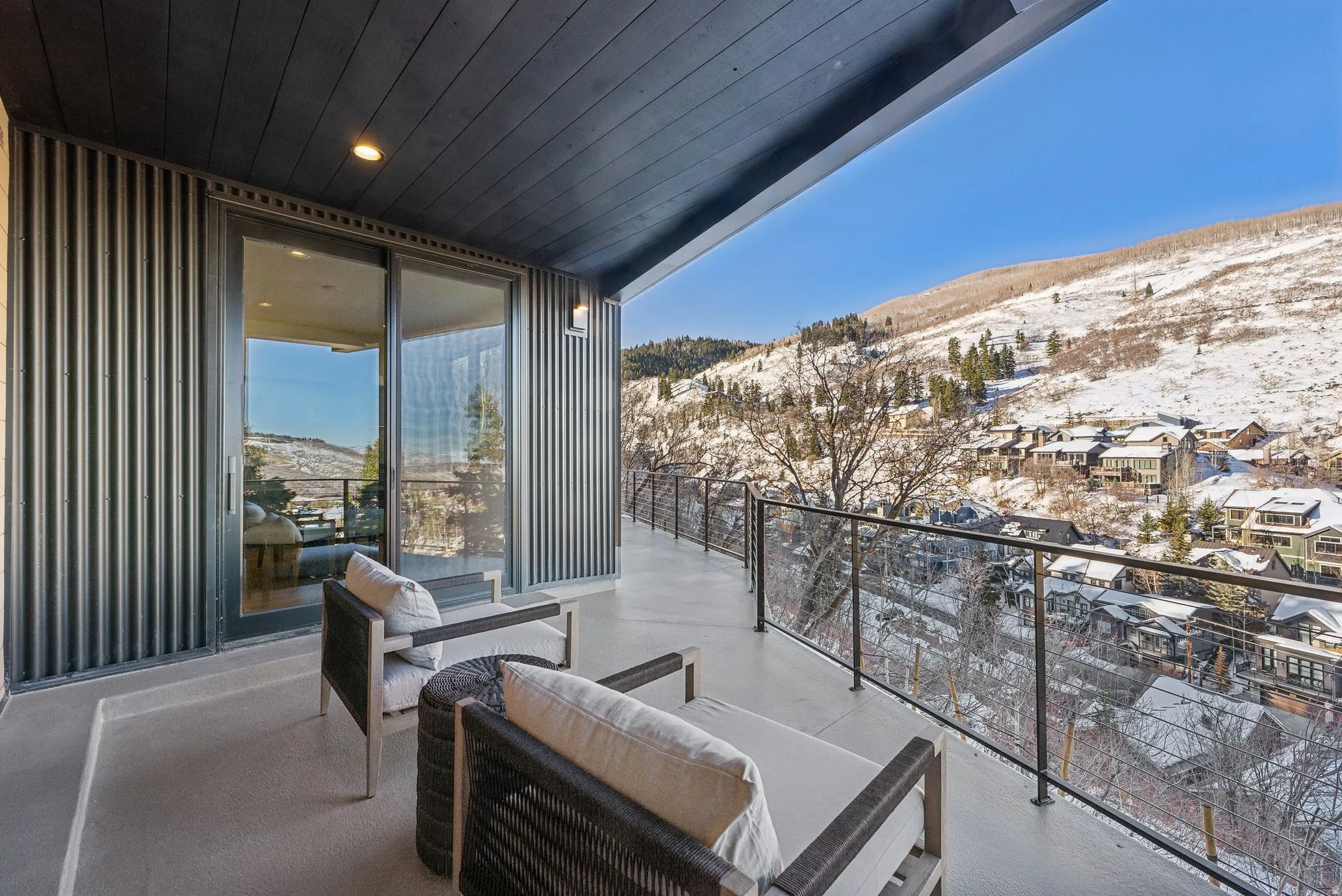 Snow covered back of property with a mountain view and an outdoor living space