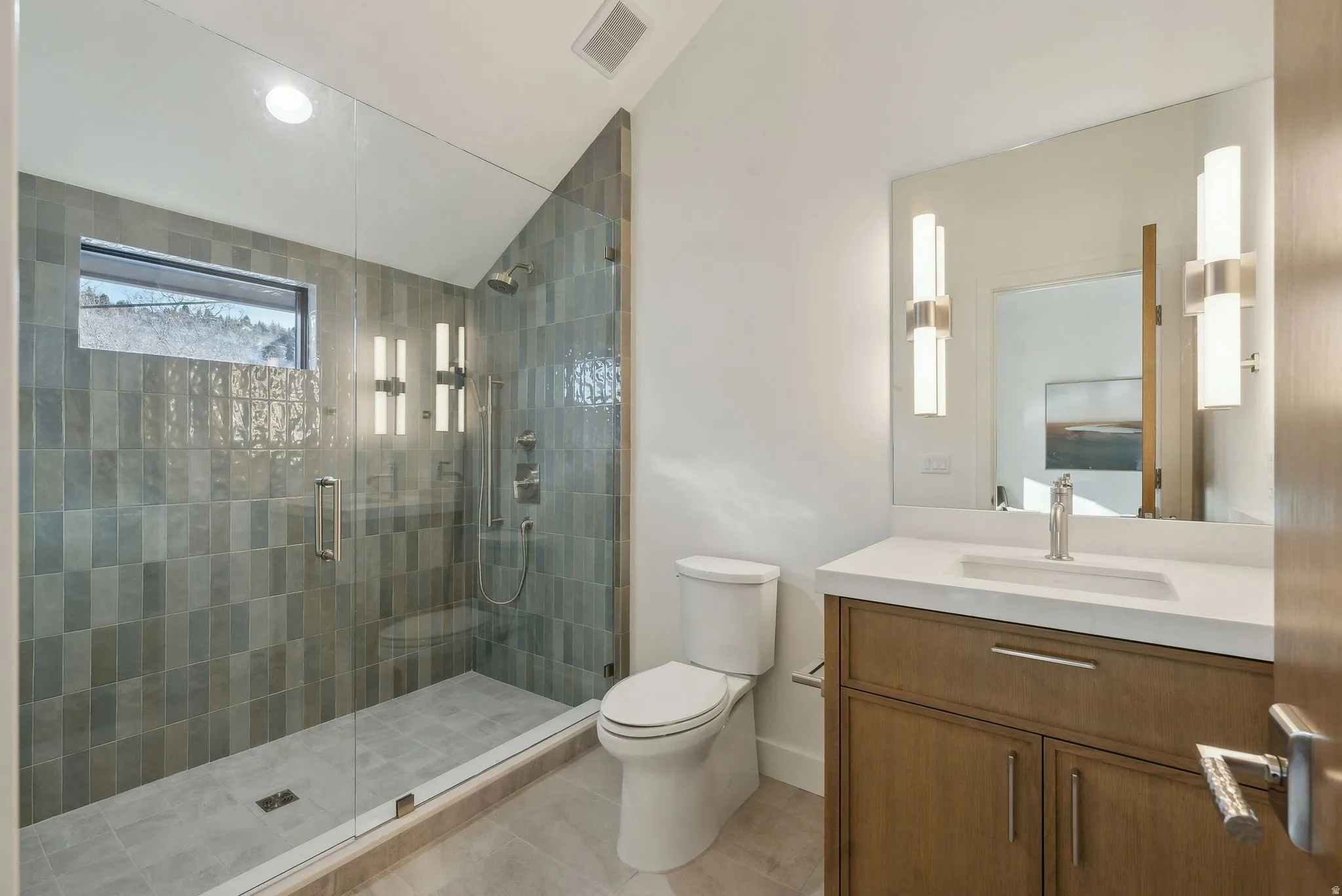 Full bath with vaulted ceiling, vanity, a stall shower, and light tile patterned floors