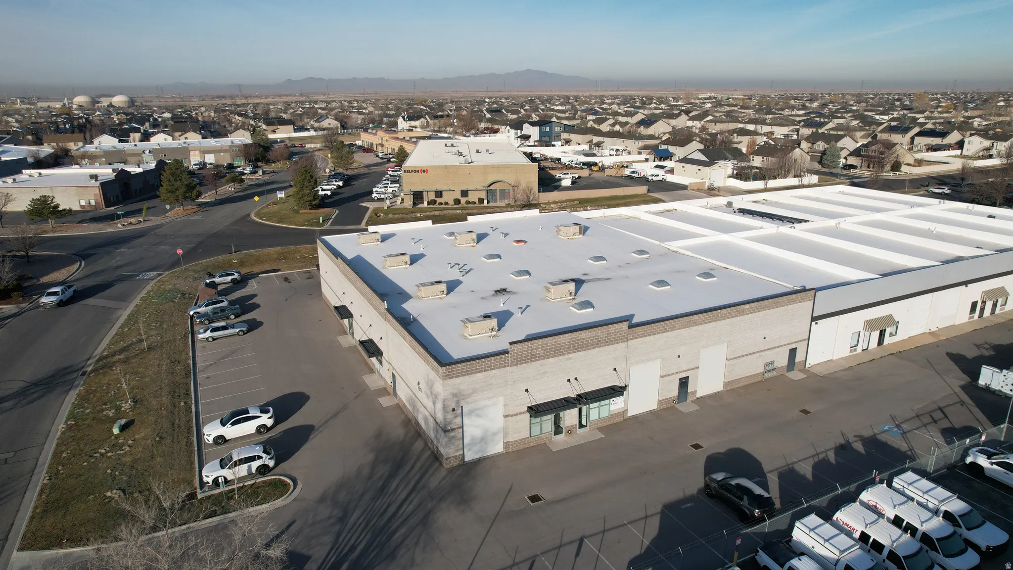 Large commercial building featuring a flat roof and ample paved parking