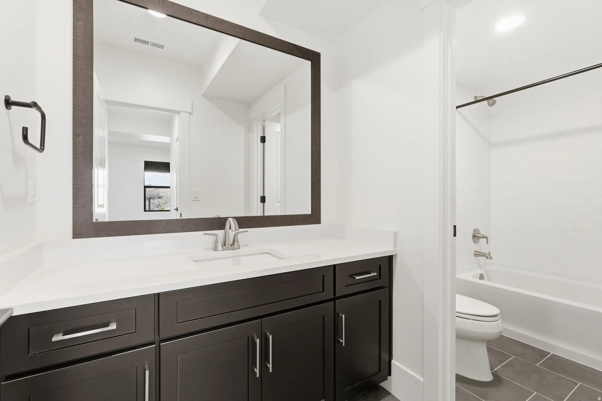 Basement Bedroom 2 Full bath with vanity, shower / tub combination, and dark tile patterned floors in Bedroom 1 in basement