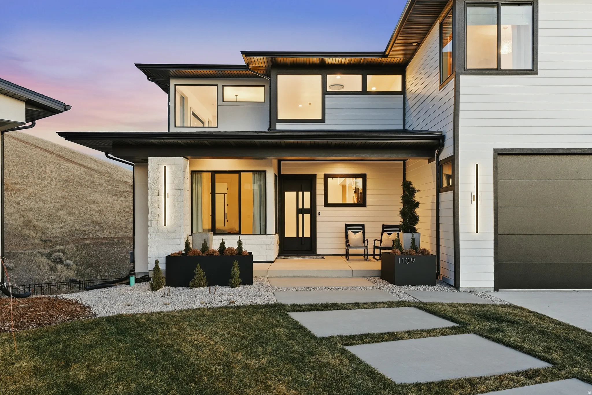 Front of property at dusk with covered porch and a yard