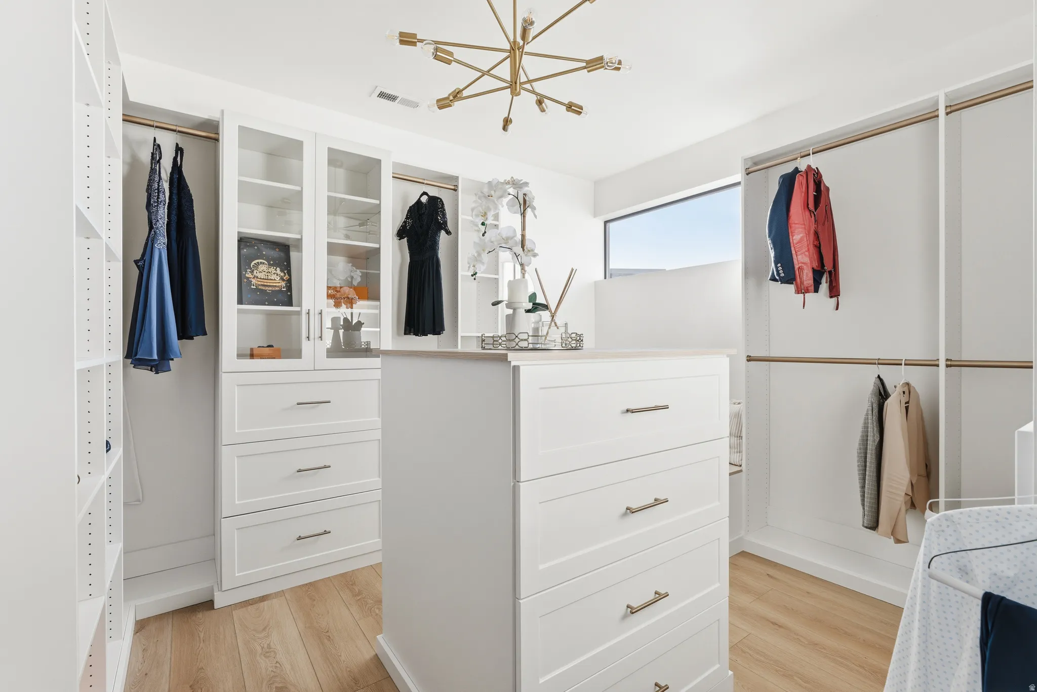 Primary Walk in closet with a chandelier and light wood-style flooring