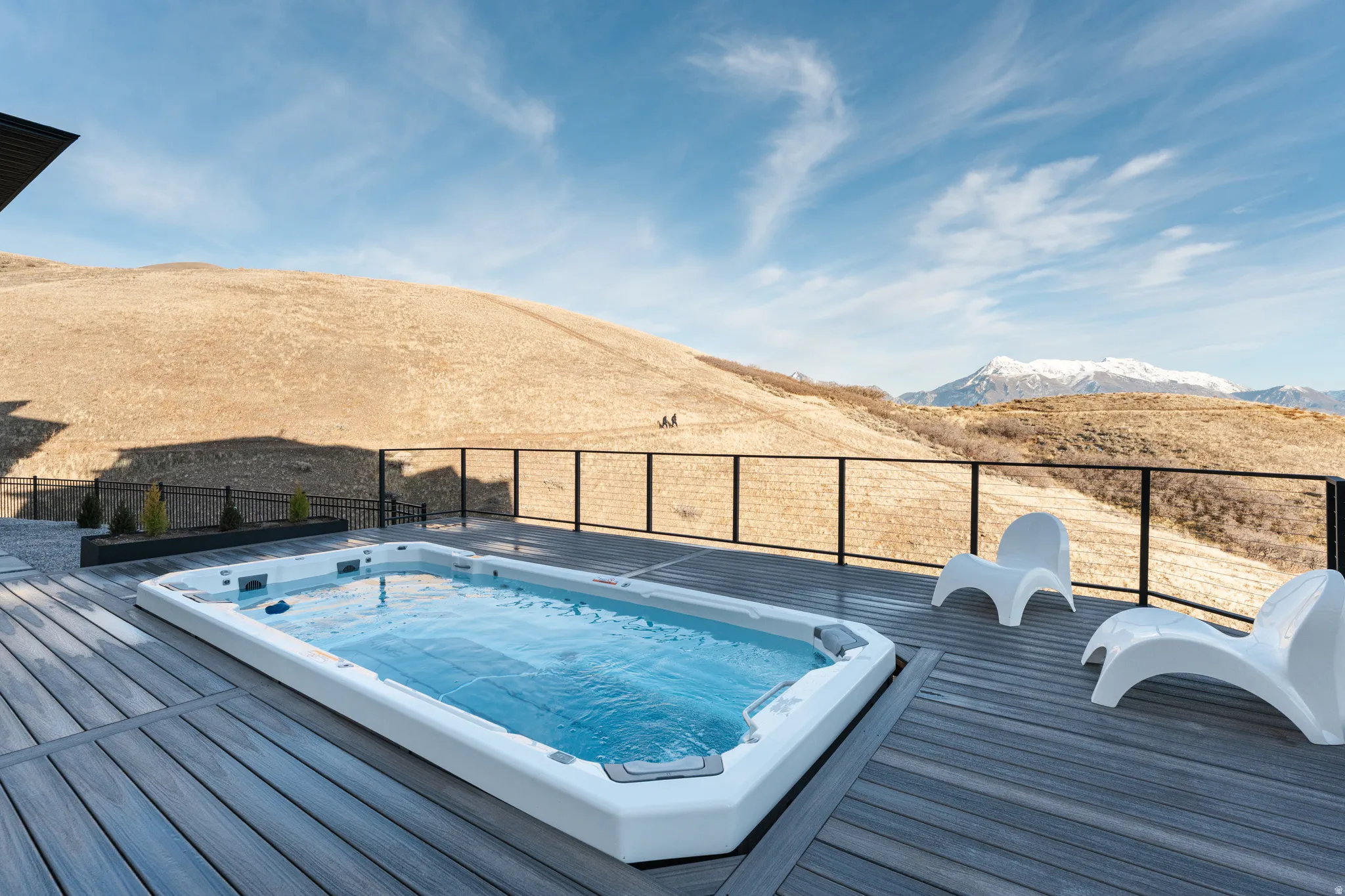 View of swimming spa with a deck with mountain view and couple hiking on local trail