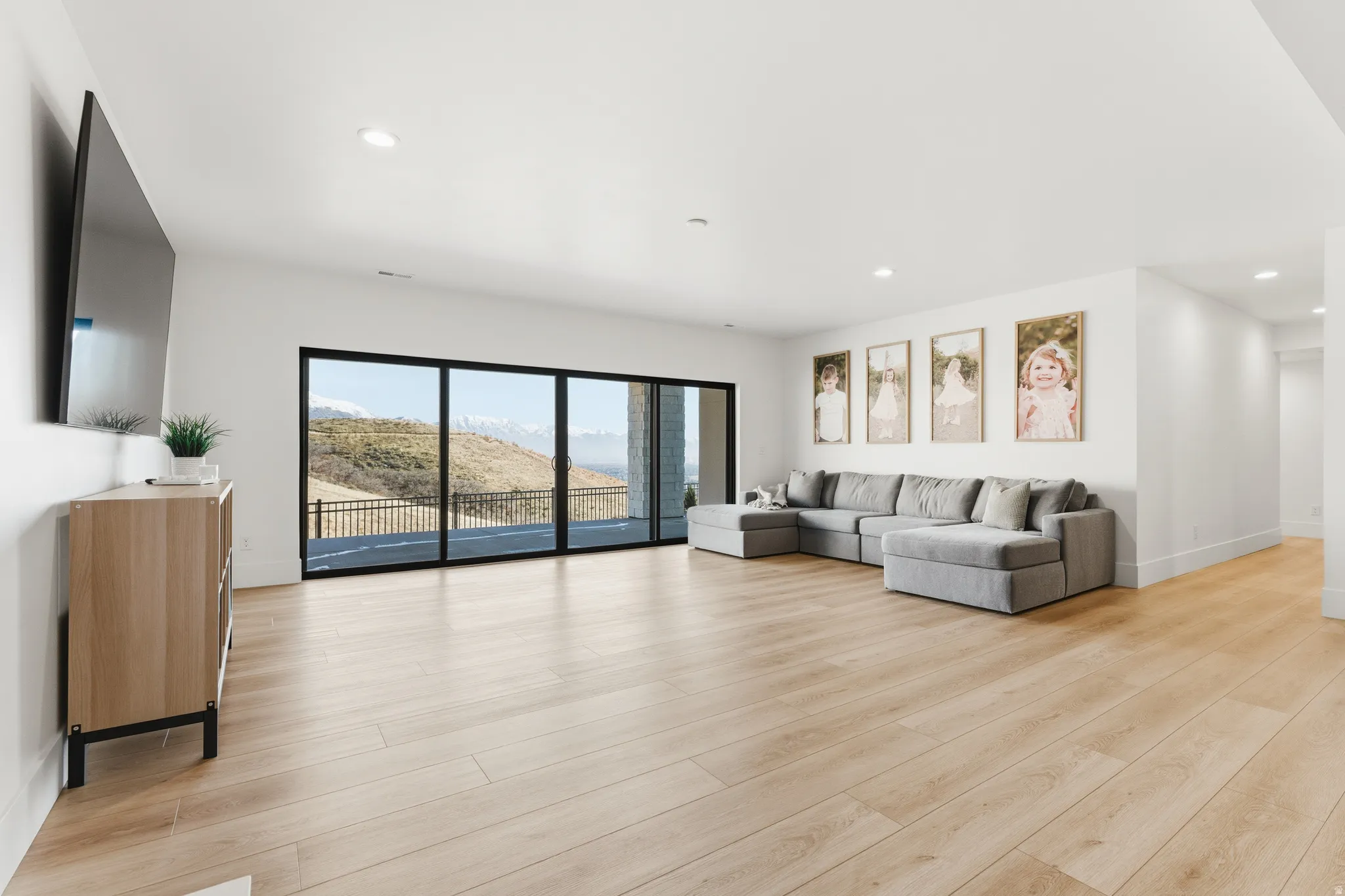 Living area with recessed lighting and light wood-style floors double wide sliding glass doors