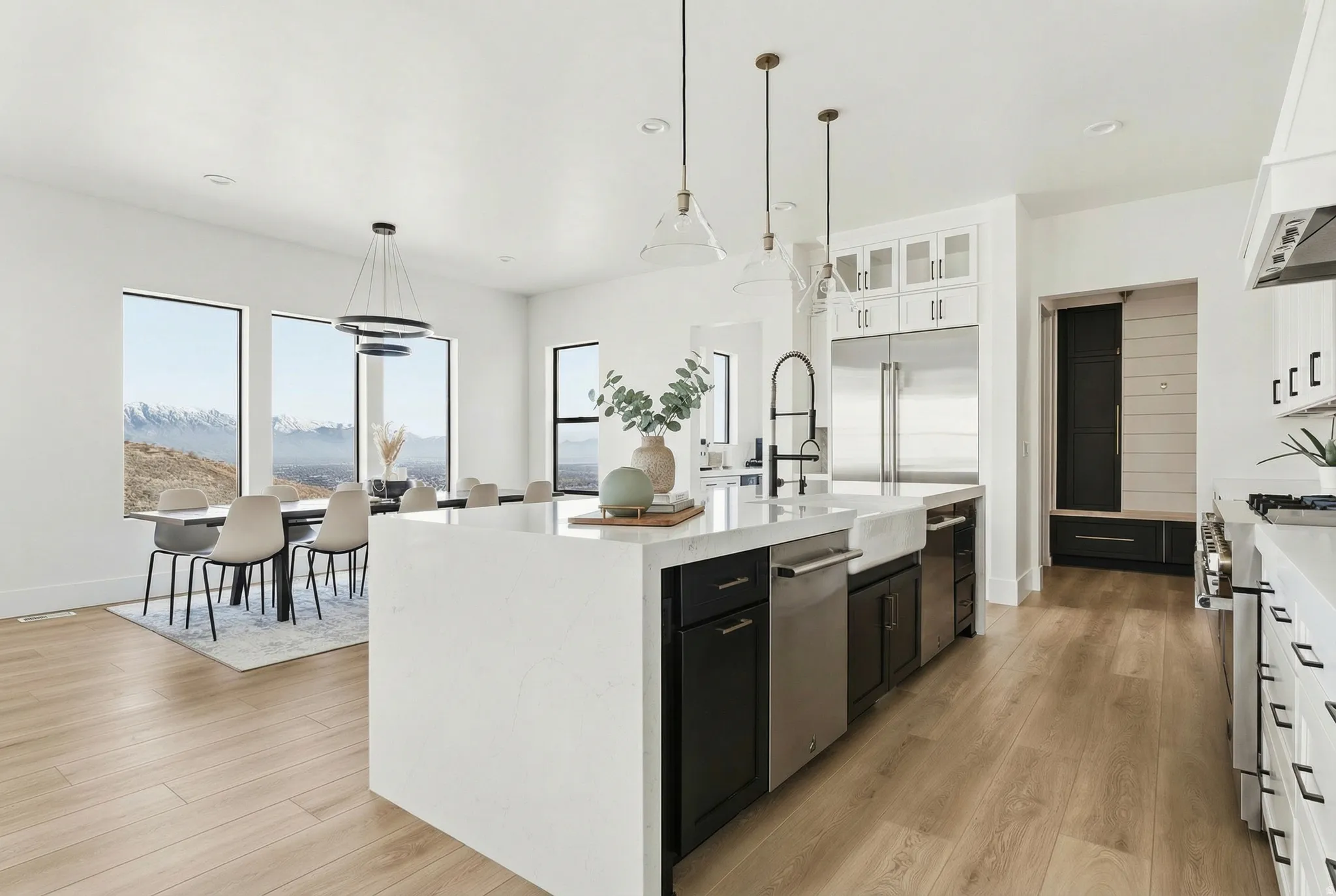 Kitchen featuring dark cabinets, light stone countertops, hanging light fixtures, light wood-style floors, and recessed lighting - Digitally Staged