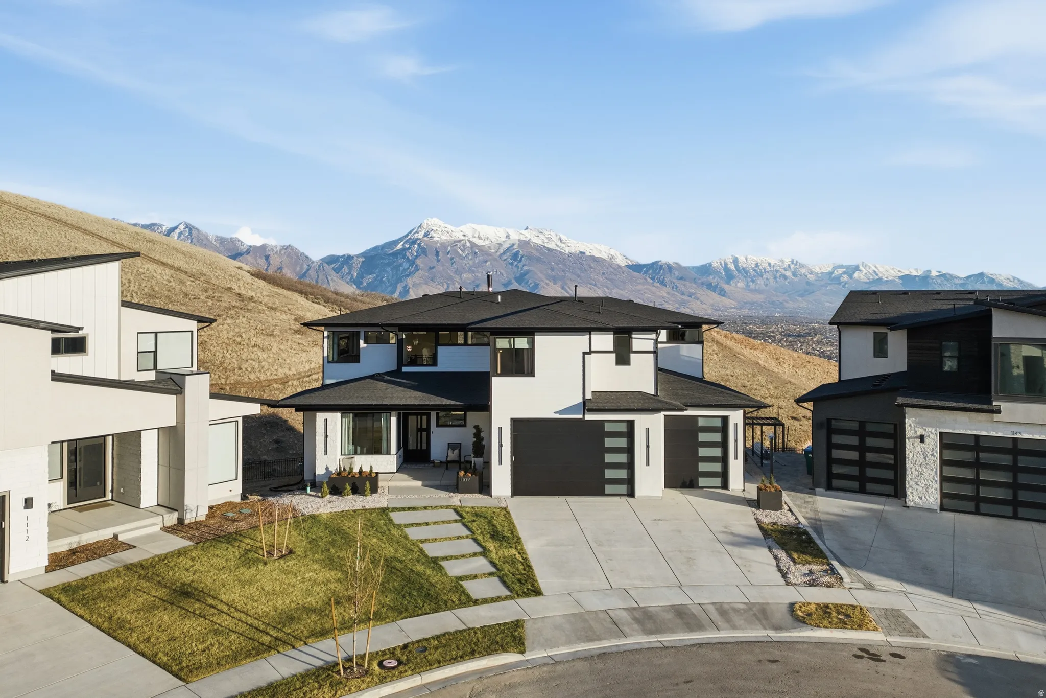 View of front of house with driveway, stucco siding, a garage, and a mountain view