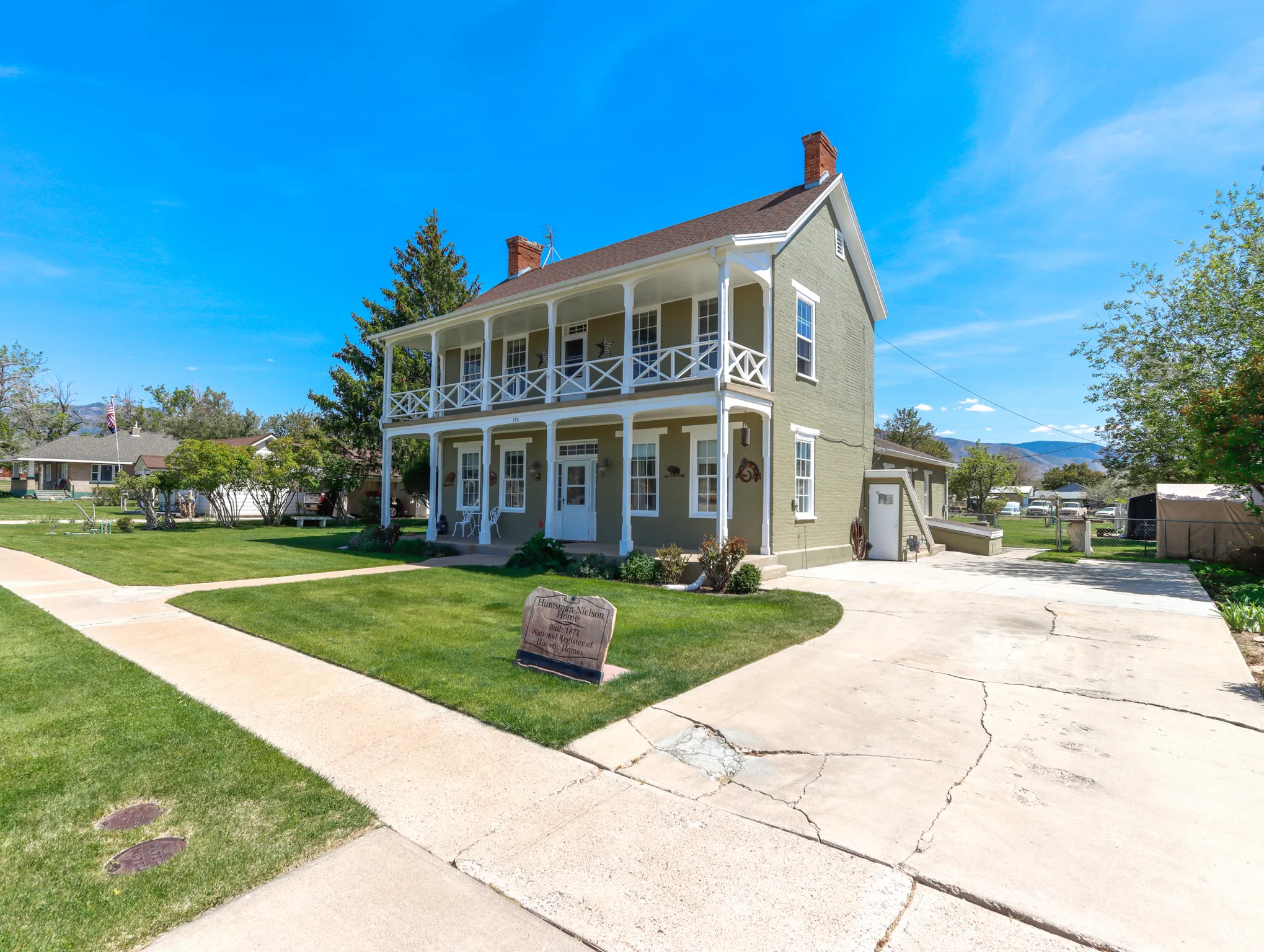 Two-story traditional residence featuring a full-width covered porch with upper-level balcony, white columns, and balusters