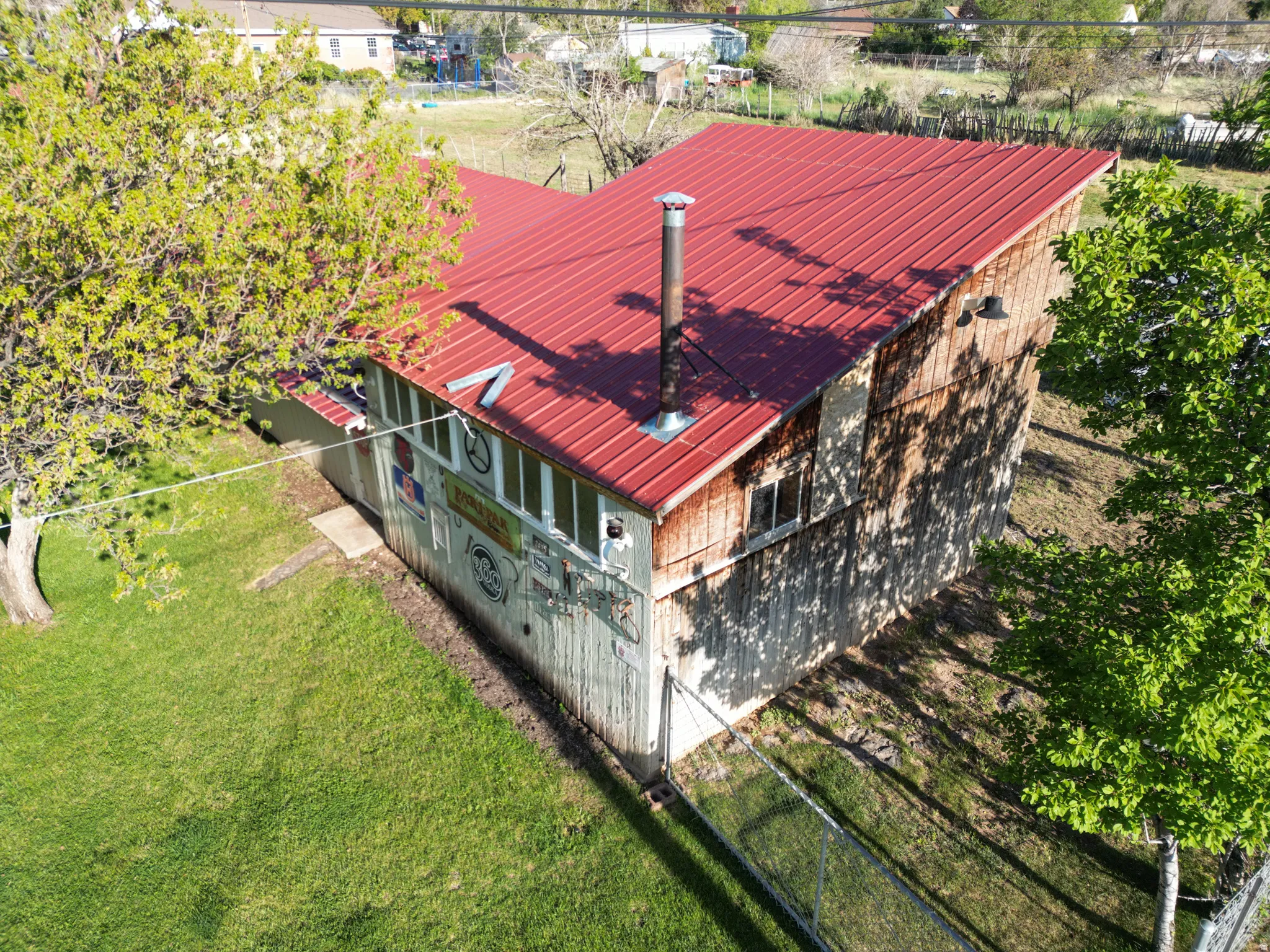 Metal roof structure featuring a chimney, wood siding, and multiple windows