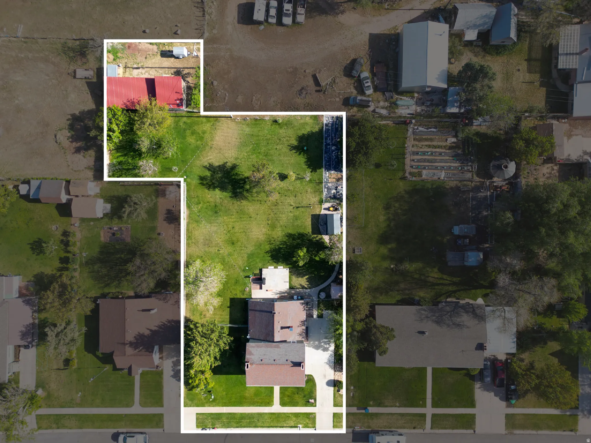 Aerial perspective showcasing a residential property with a primary dwelling, extensive green space, and an additional red-roofed structure