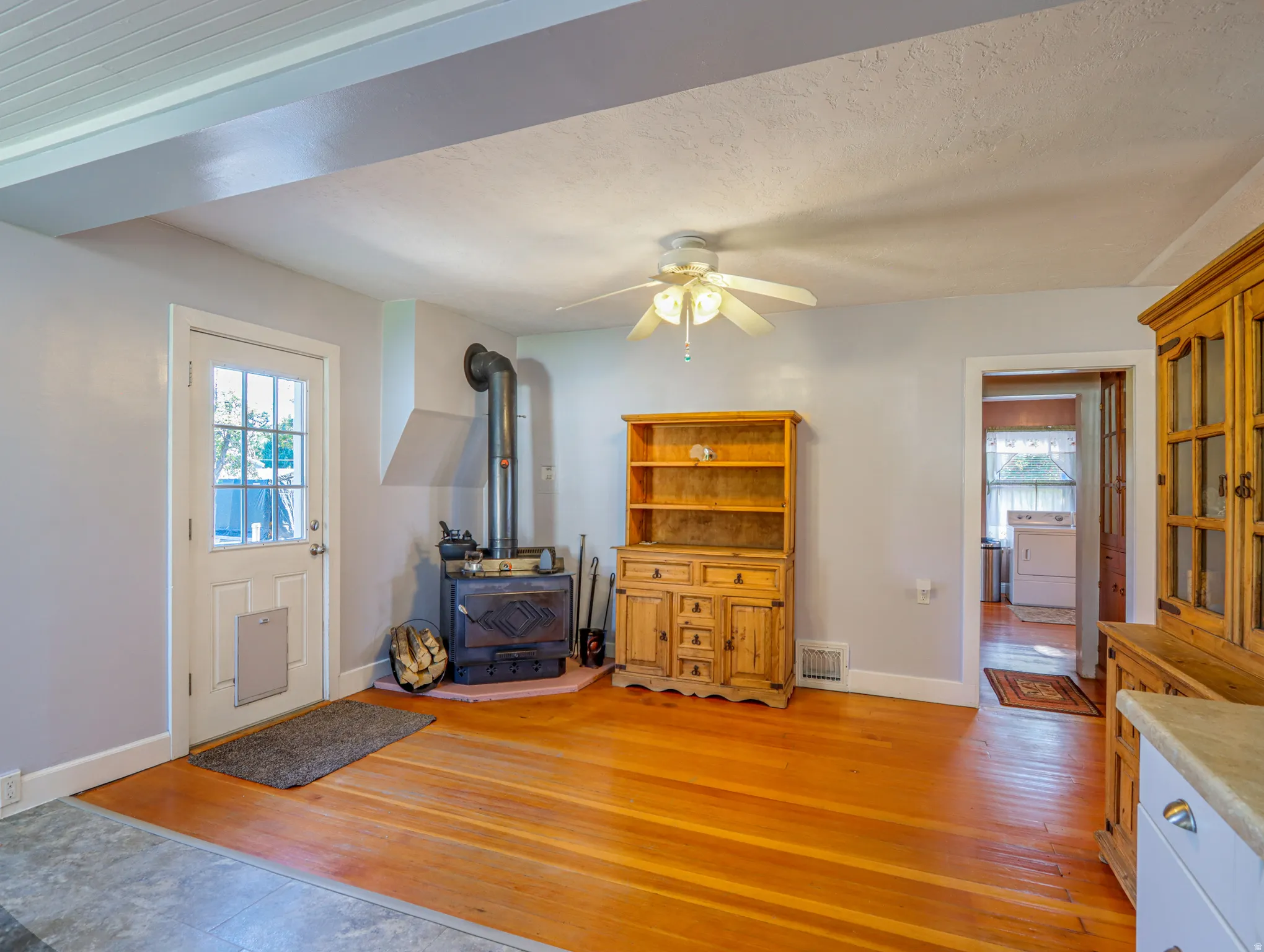 Hardwood flooring complements a traditional wood-burning stove with a corner hearth pad