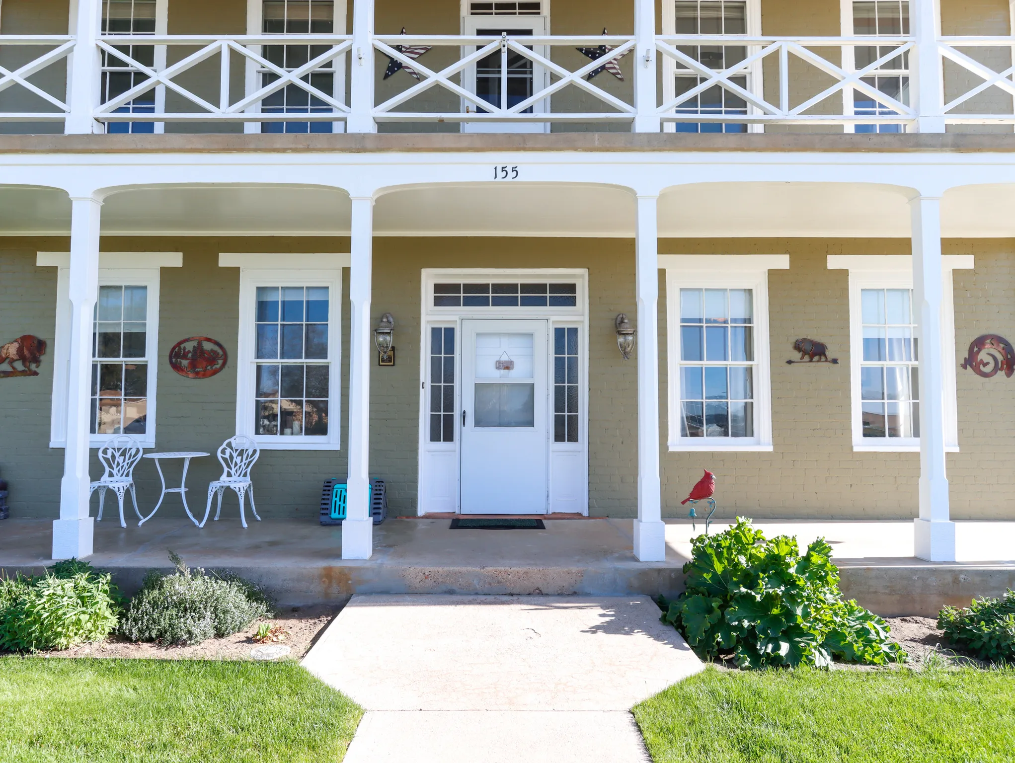 Exterior facade featuring a covered porch with white columns, a second-story balcony with decorative railing, and multiple double-hung windows