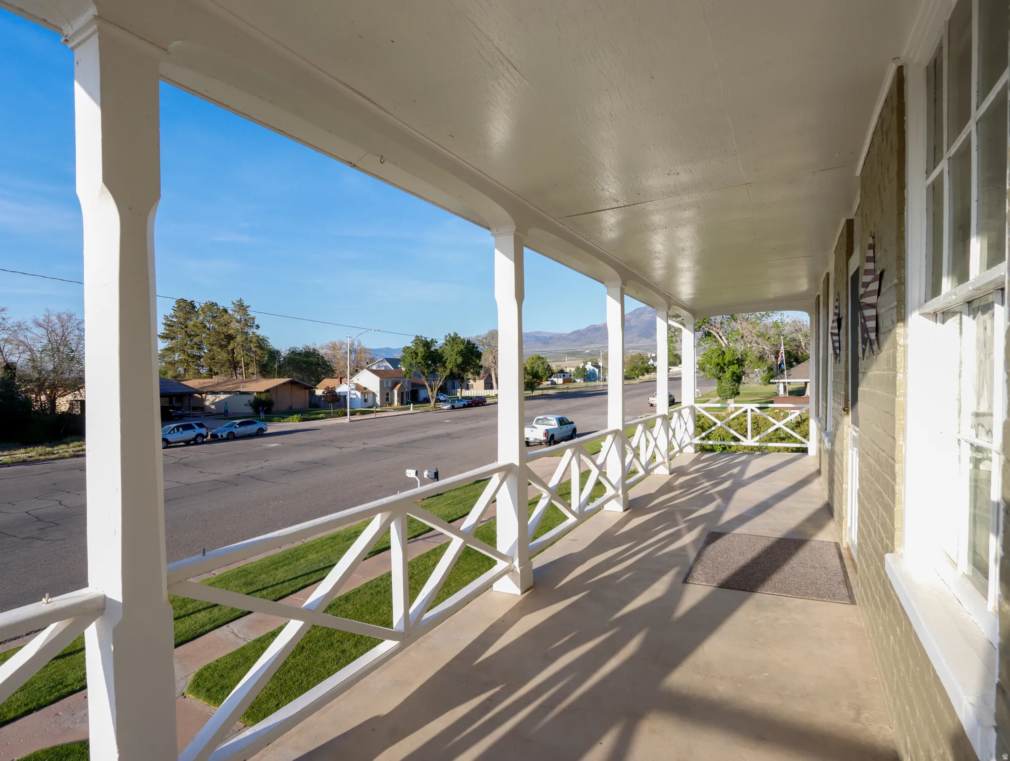 Spacious covered front porch featuring white pillars and a decorative railing