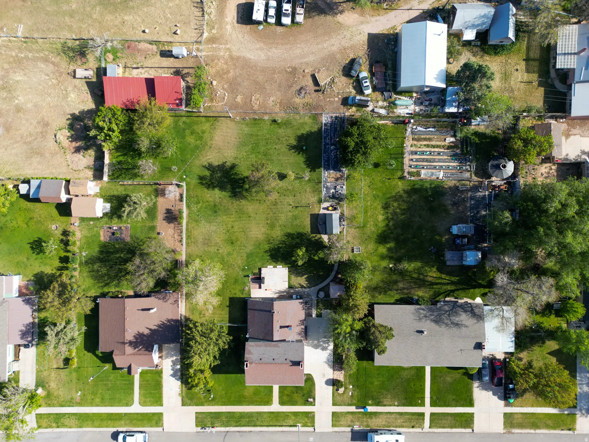 Expansive property featuring a large grassy lot, mature trees, and multiple outbuildings