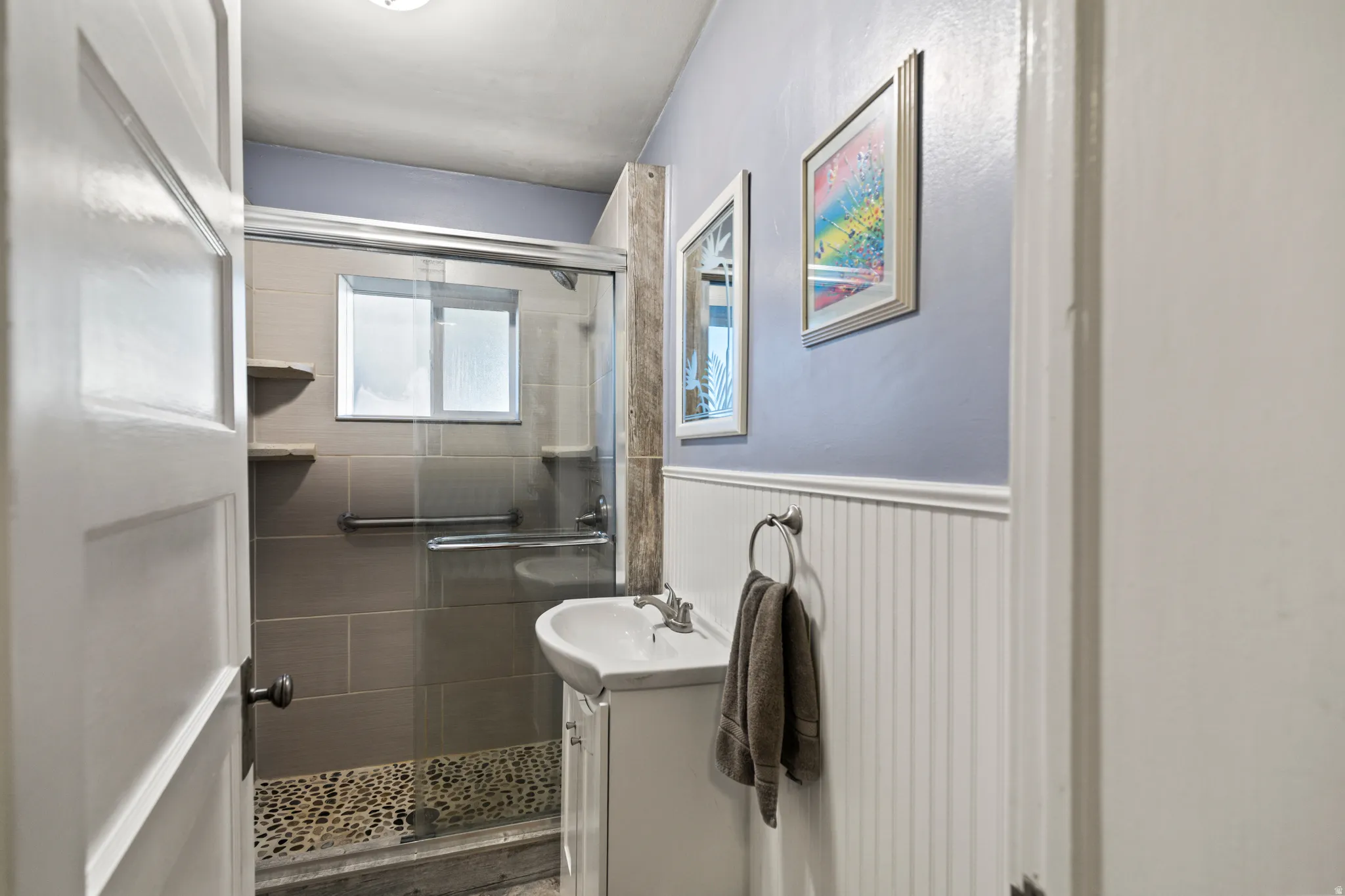 Bathroom with vanity, a stall shower, and a wainscoted wall