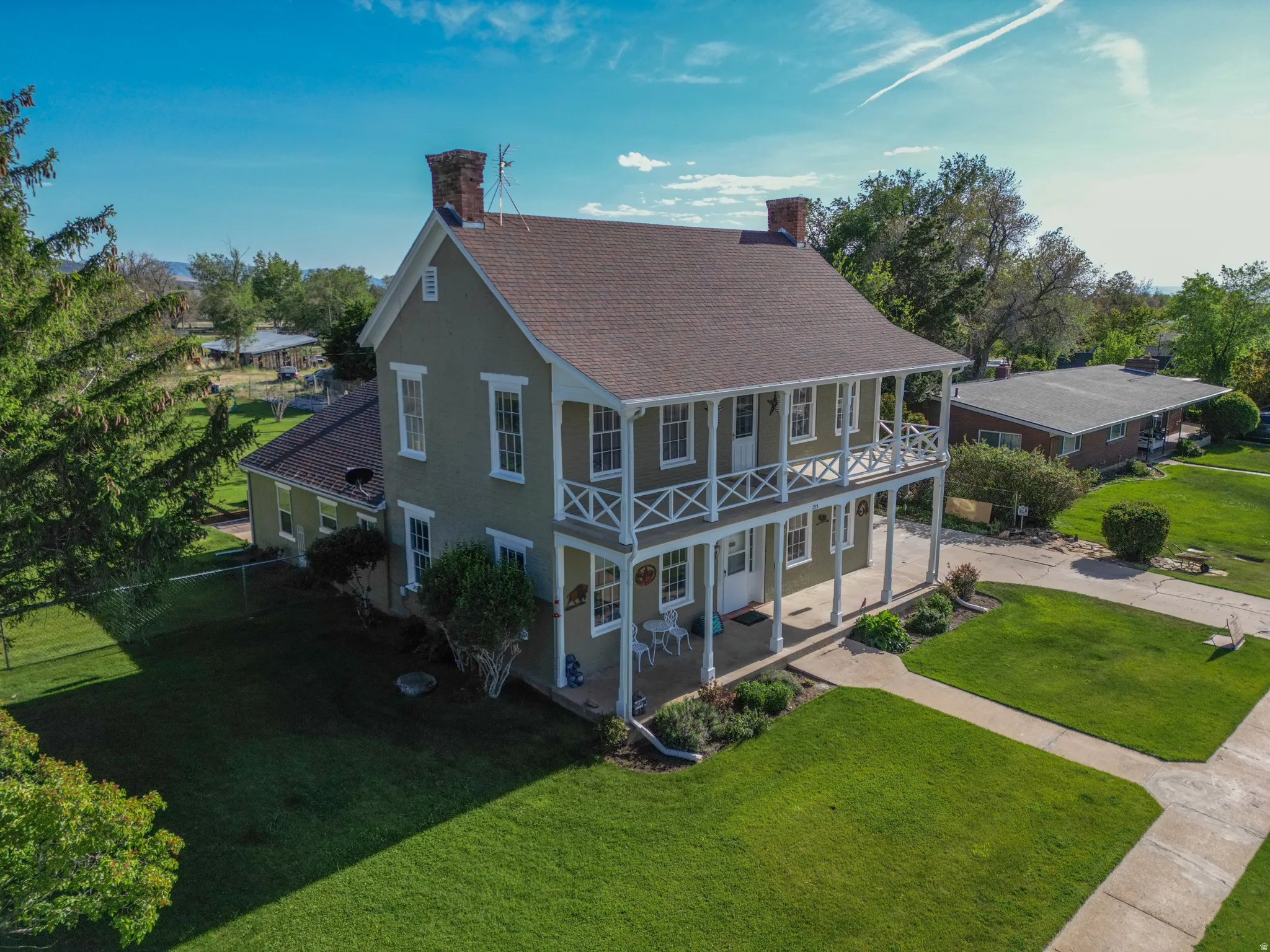 Two-story colonial-style residence featuring a full-width covered porch and upper balcony with decorative railings