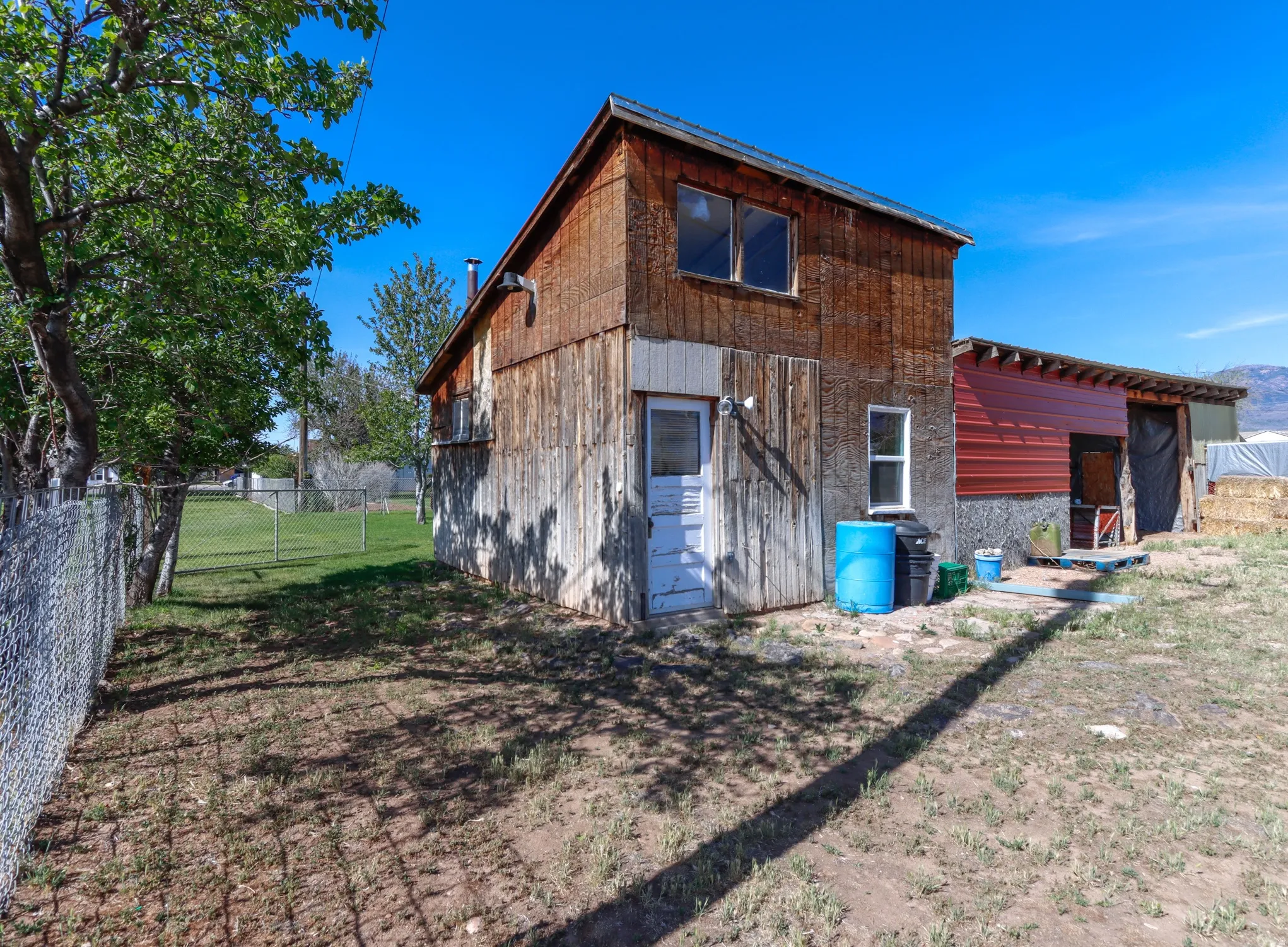 Wood-sided structure with a red corrugated metal extension