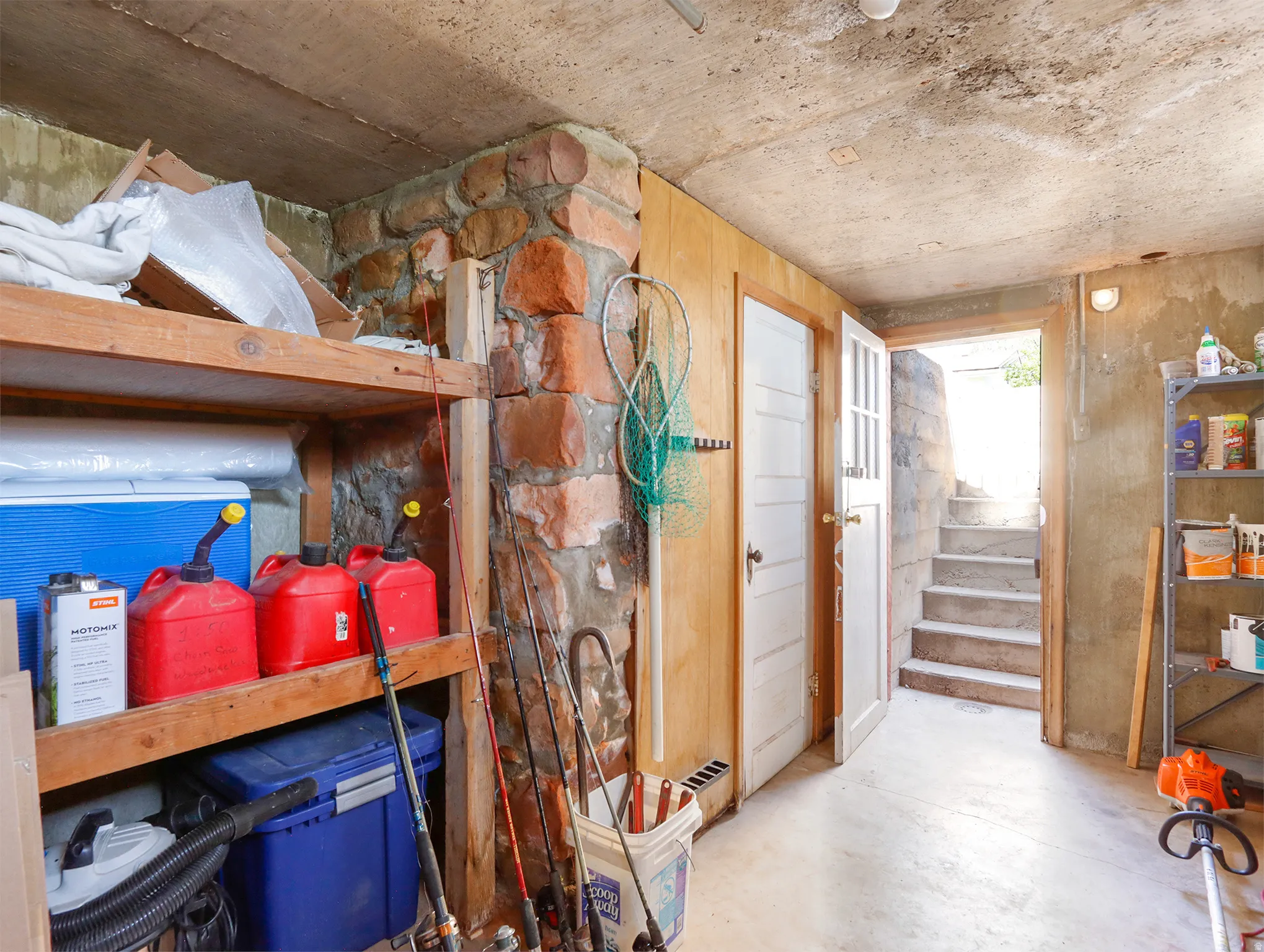 Functional unfinished basement area featuring concrete flooring and a stone-clad accent wall