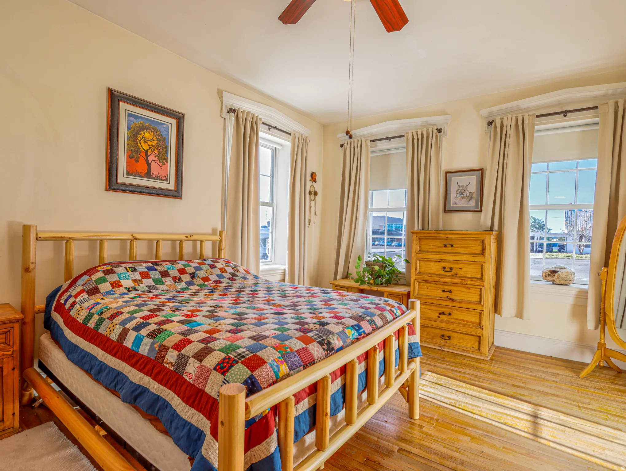 Room featuring two large windows with drapes, a ceiling fan, and light-toned wood-finish flooring