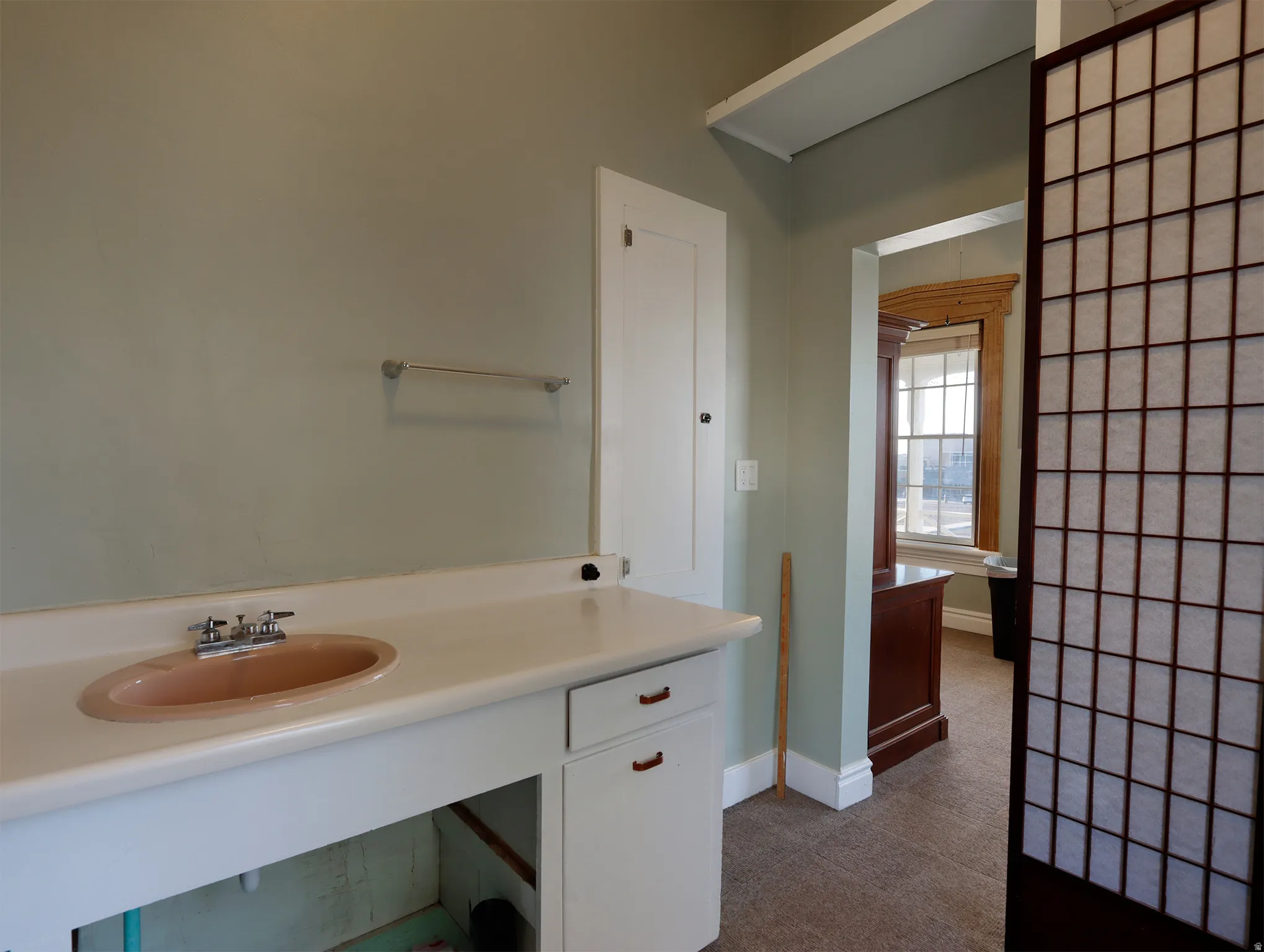 Vanity area featuring a built-in countertop with an oval sink, chrome faucet, and cabinet storage