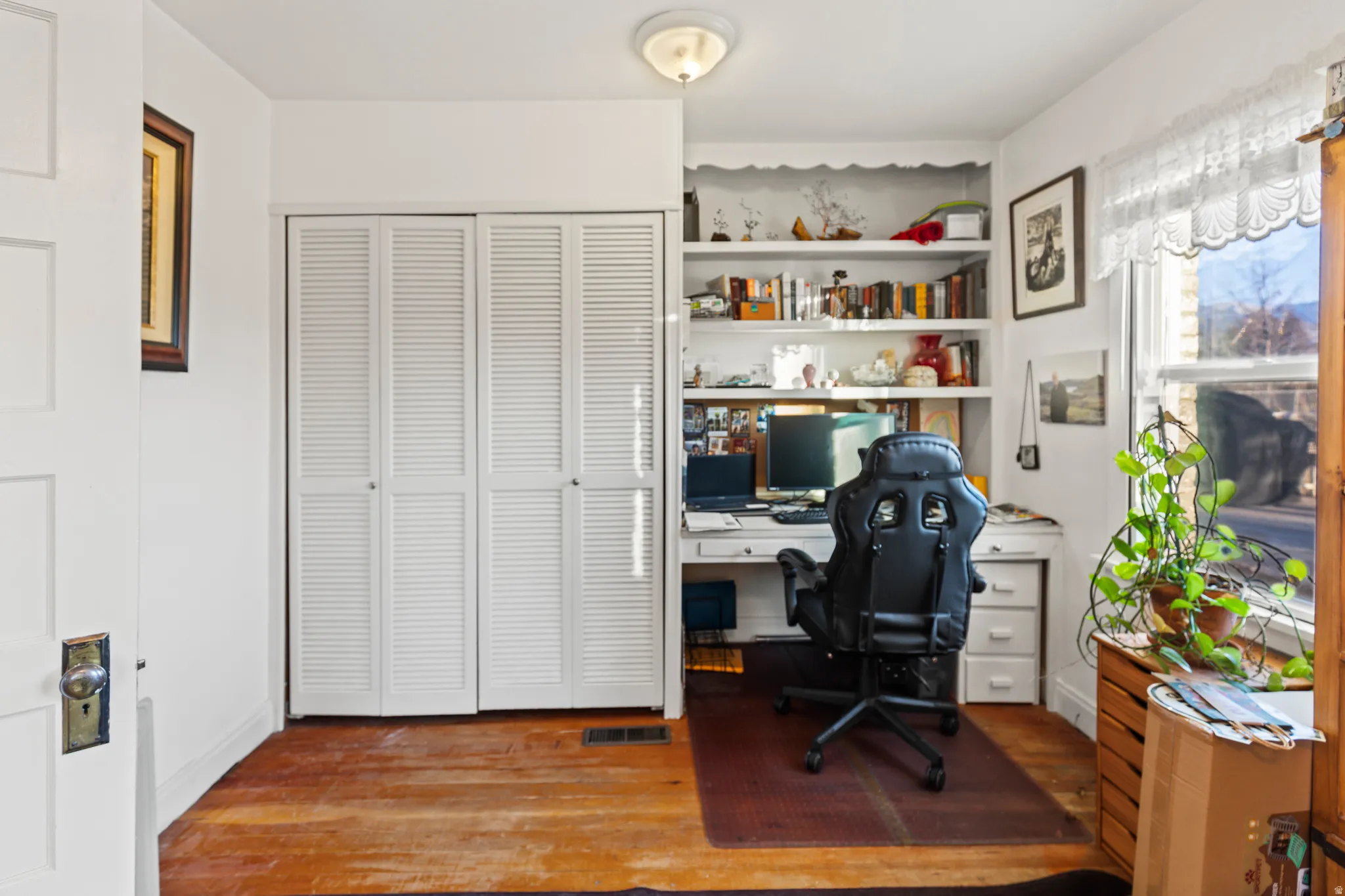 Office with wood finished floors and built in shelves