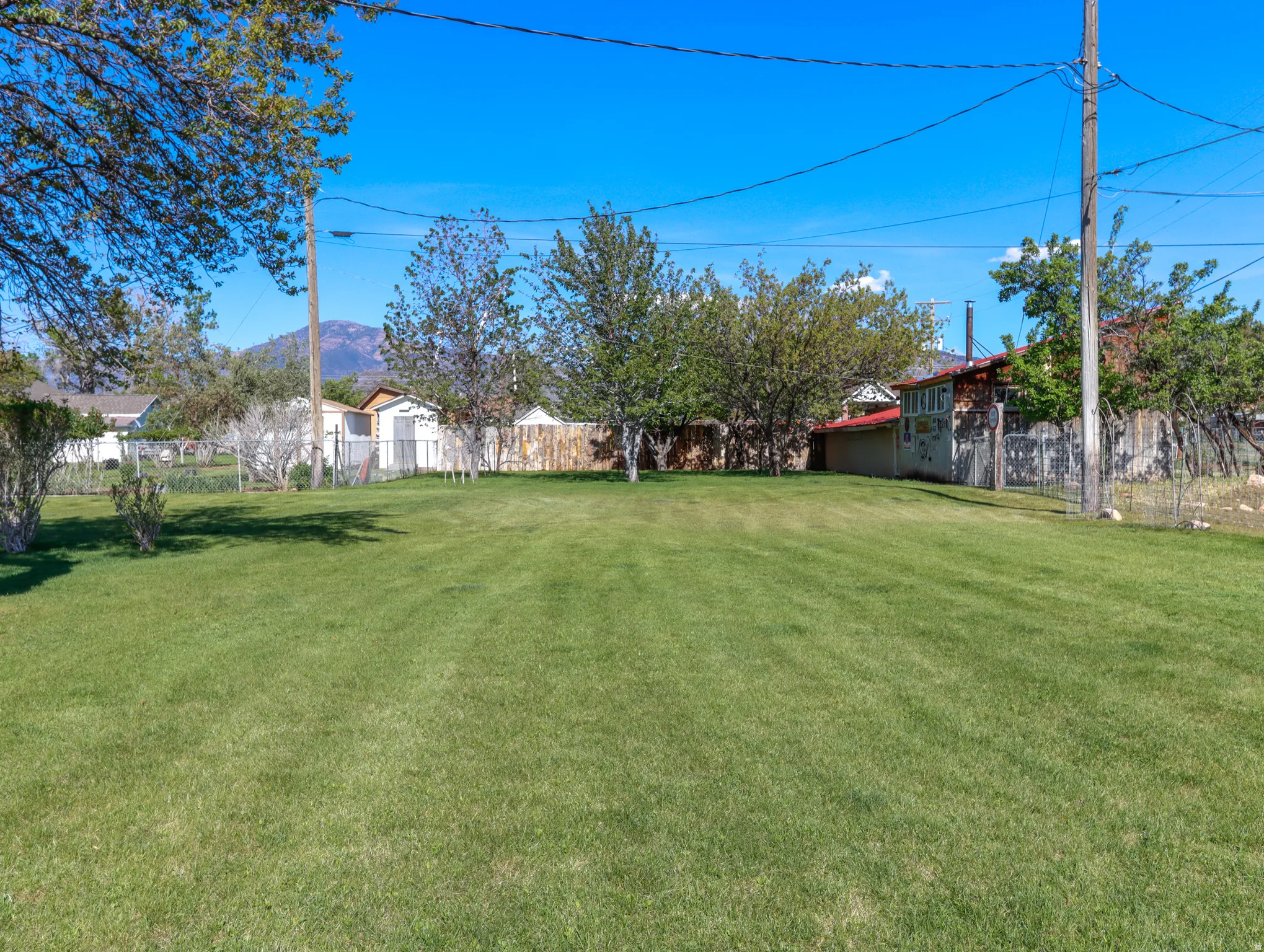 Expansive green lawn with mature trees and a distant mountain backdrop