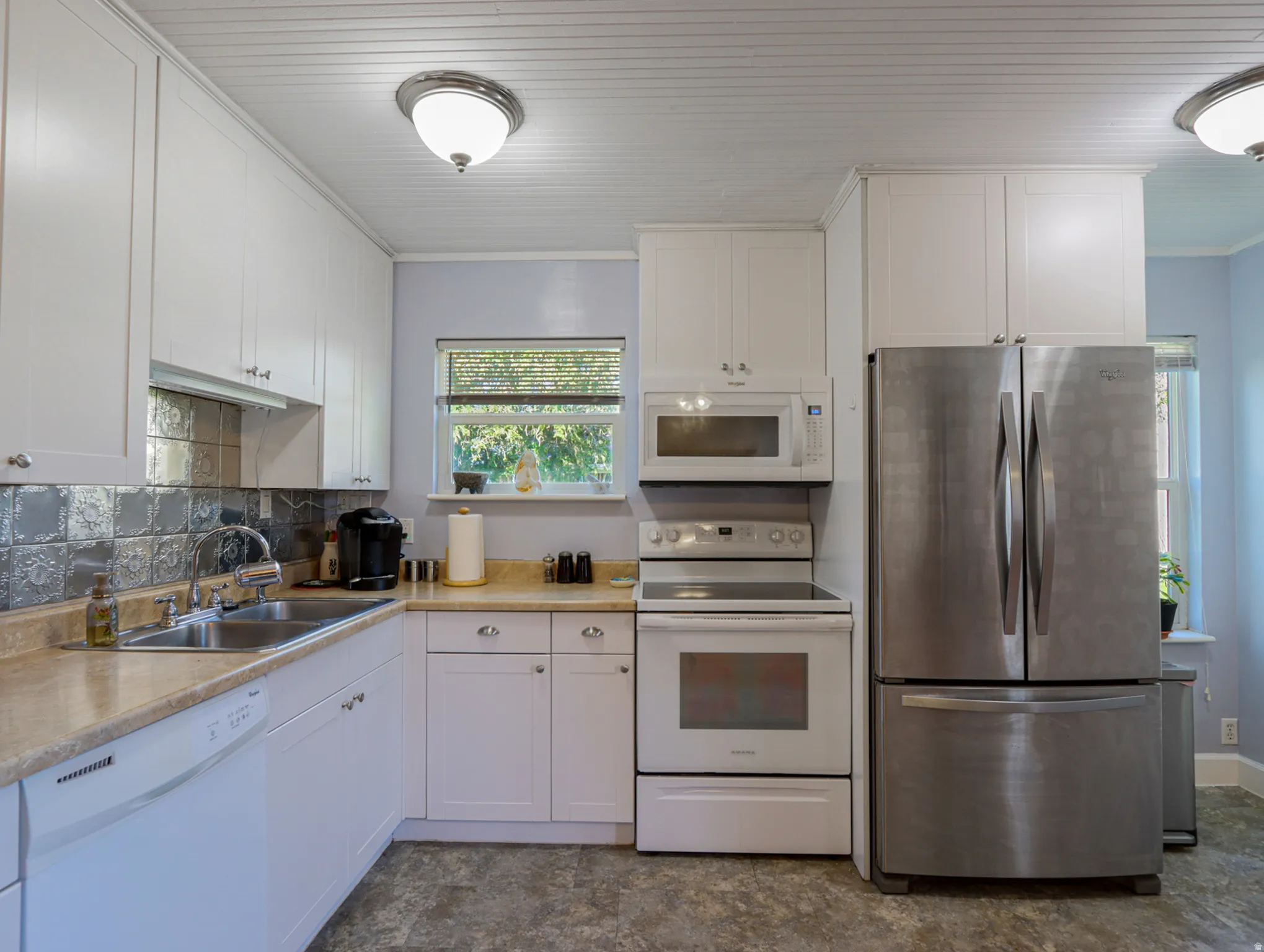 Kitchen featuring white cabinetry, light-toned countertops, a stainless steel French door refrigerator, a white electric range, and a built-in microwave
