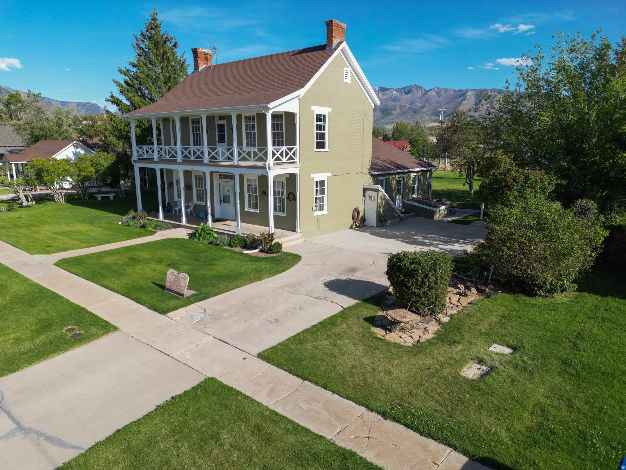 Two-story residence featuring a covered front porch and upper-level balcony with white railings