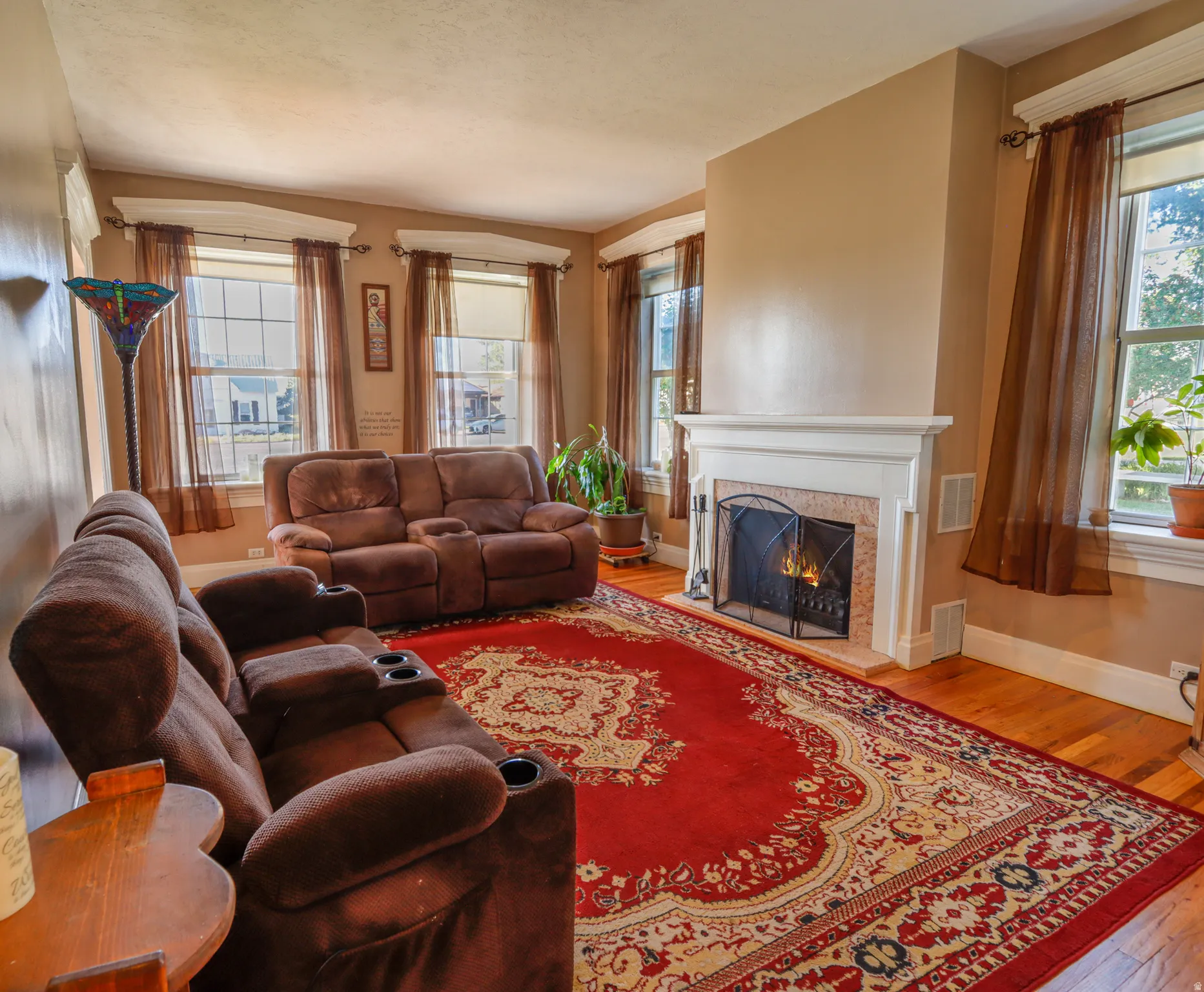 Hardwood flooring throughout the room, complemented by a white fireplace mantel and a tiled firebox