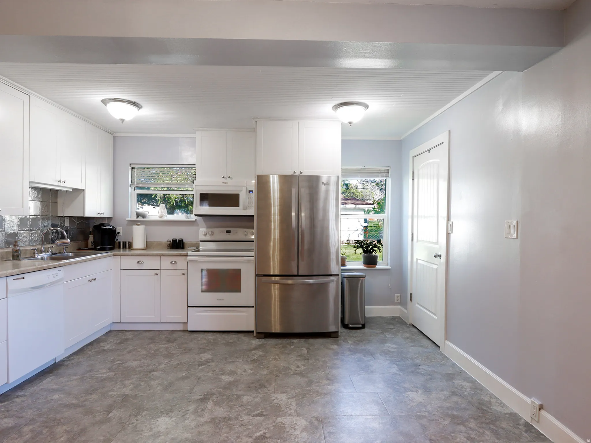Kitchen featuring white cabinetry, stainless steel refrigerator, white range, and built-in microwave