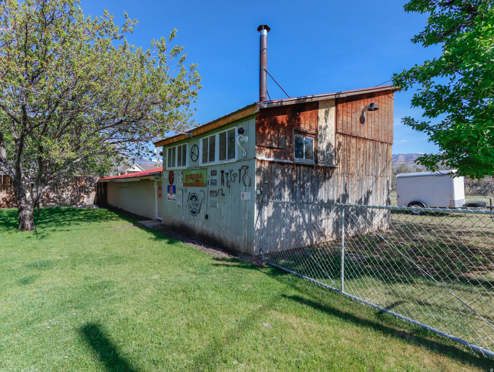Detached structure featuring wood siding, multiple windows, and an exterior chimney