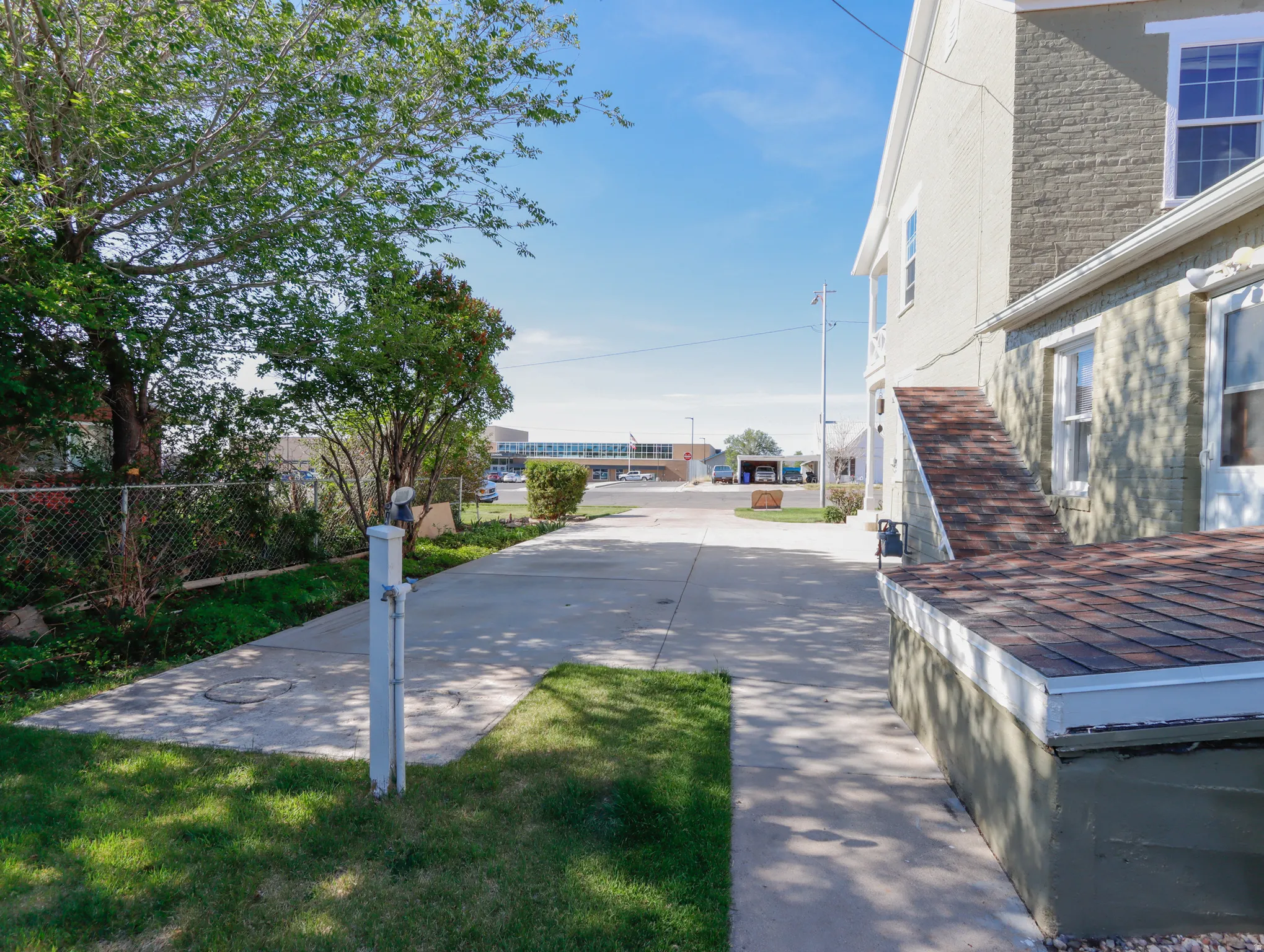 Concrete driveway and walkway bordered by green lawn and mature trees