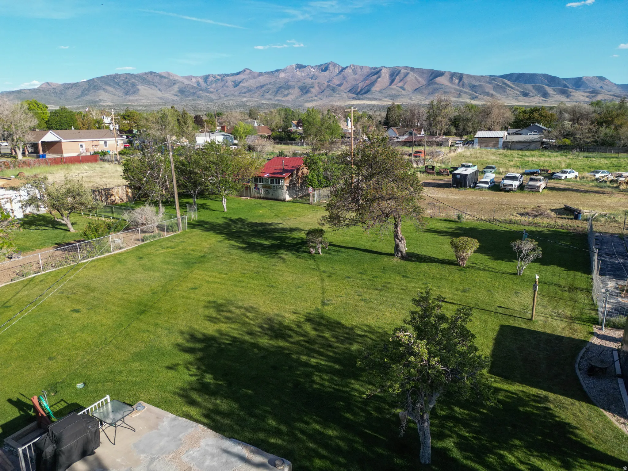 Expansive green lawn with mature trees and a concrete patio