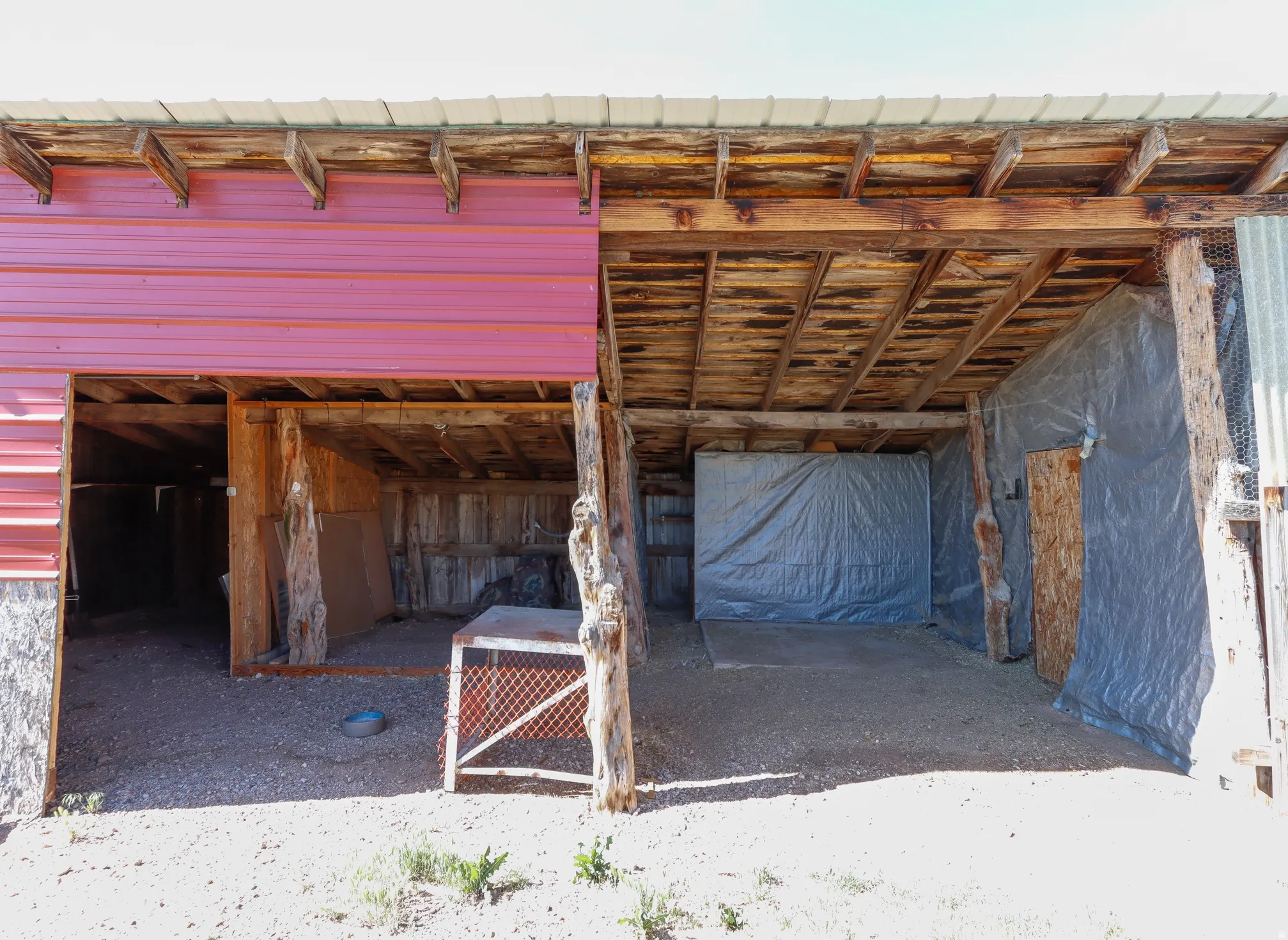 Open-air utility structure featuring a metal roof and exposed wood beam supports