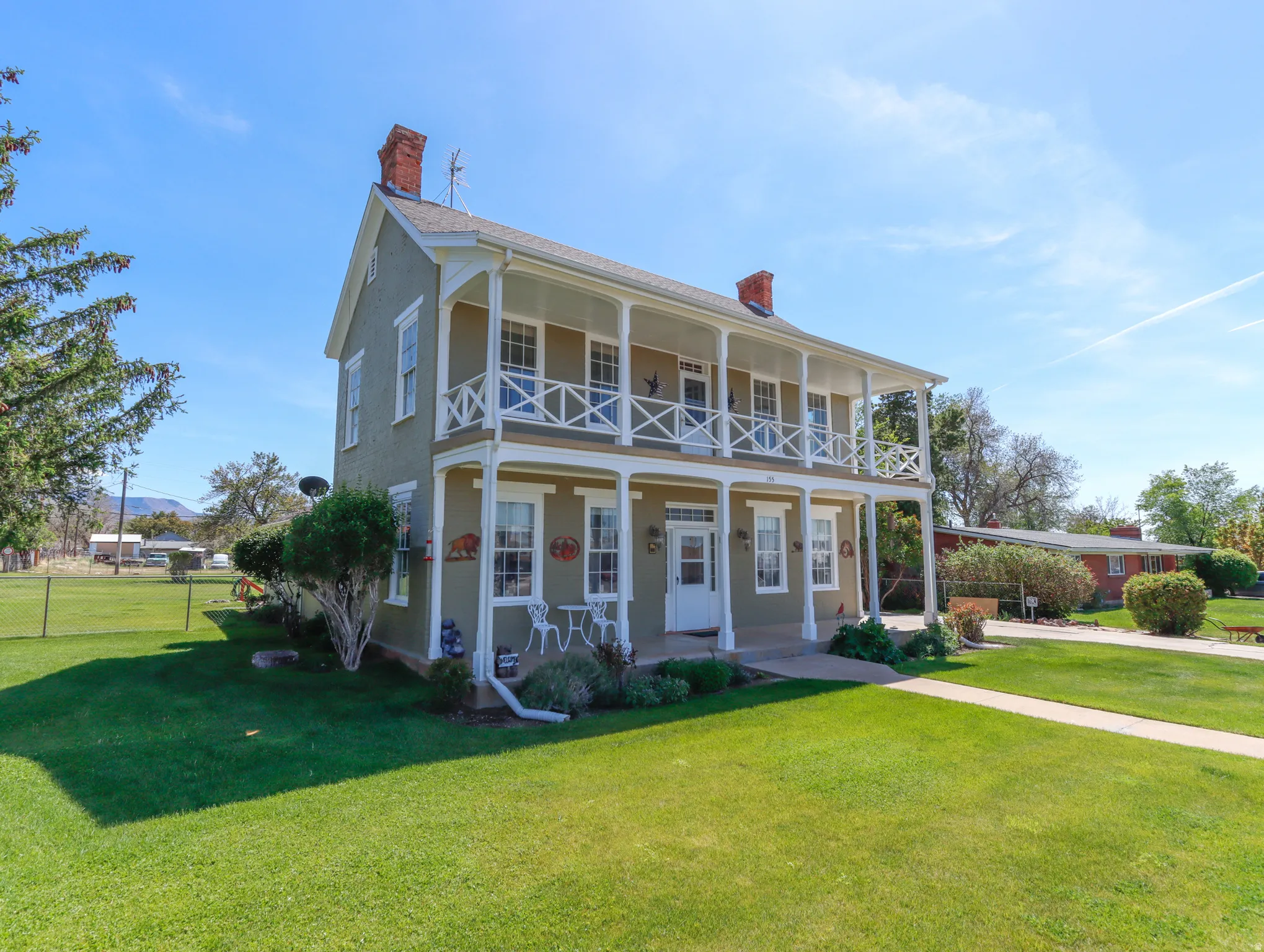 Two-story residence featuring a full-width covered porch and second-story balcony with decorative railings