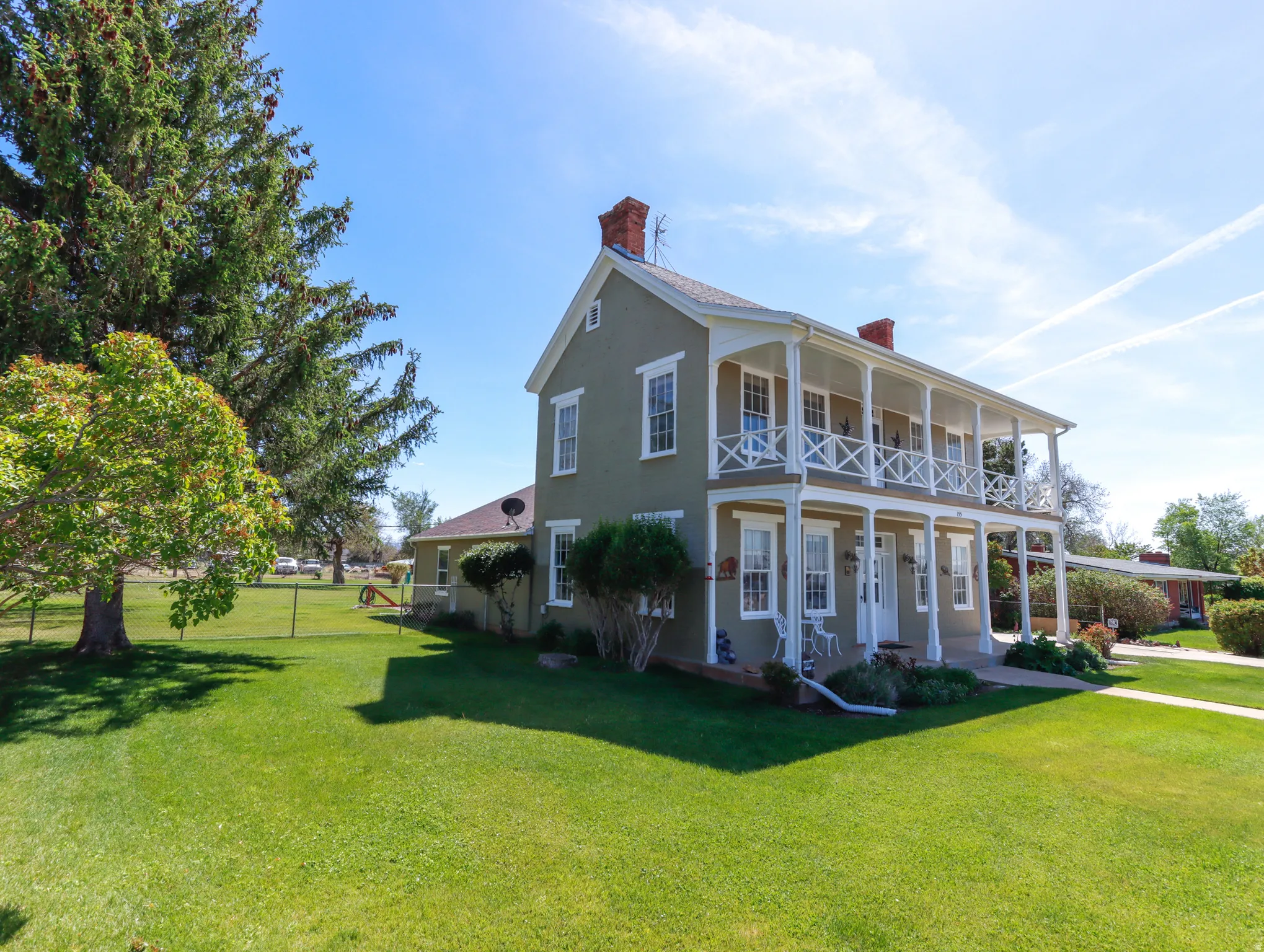 Two-story residence featuring a full-width covered porch and upper-level balcony with white railings